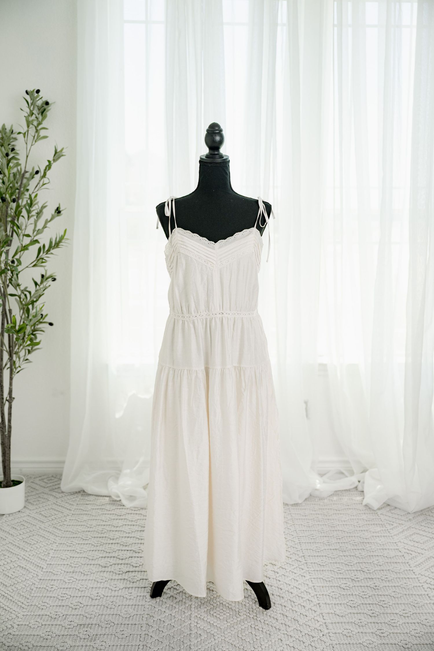 White spaghetti strap tiered maxi dress on black mannequin.