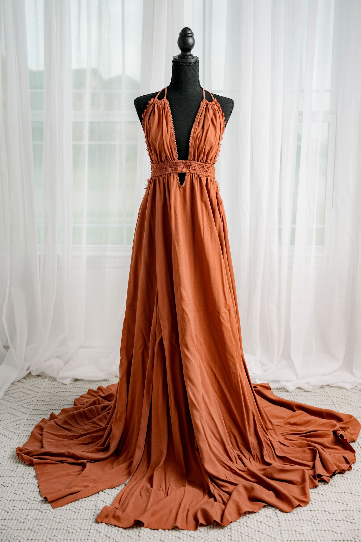 Burnt orange halter deep V-neck maxi dress with front slit on black mannequin.