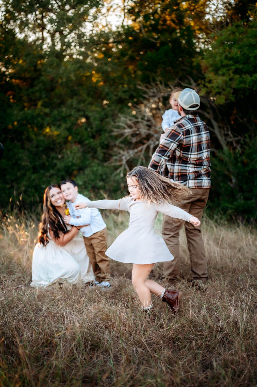 Playful couple spins and dances together in a rustic field at sunset.