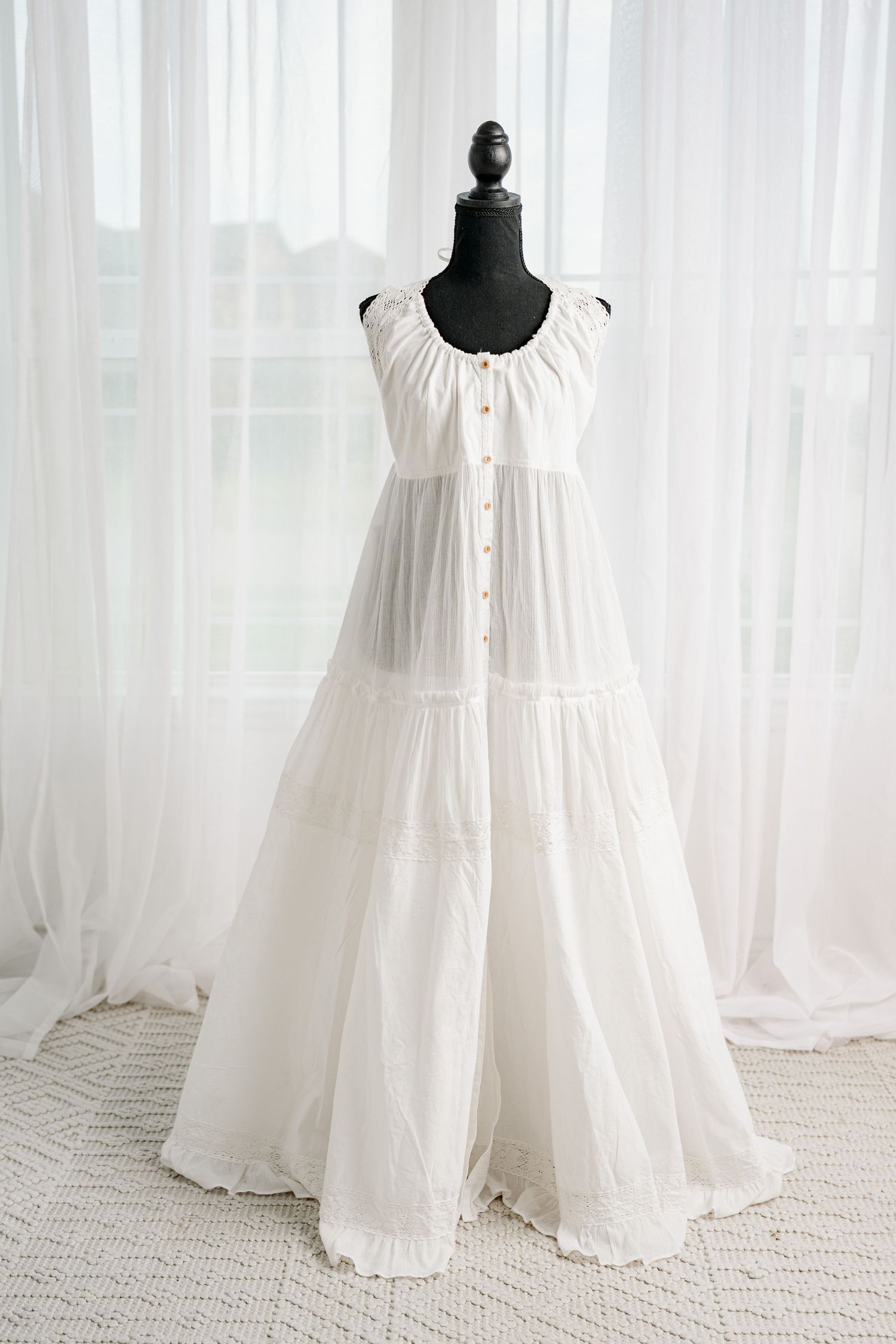 White sleeveless tiered maxi dress with button front and gathered neckline on mannequin.