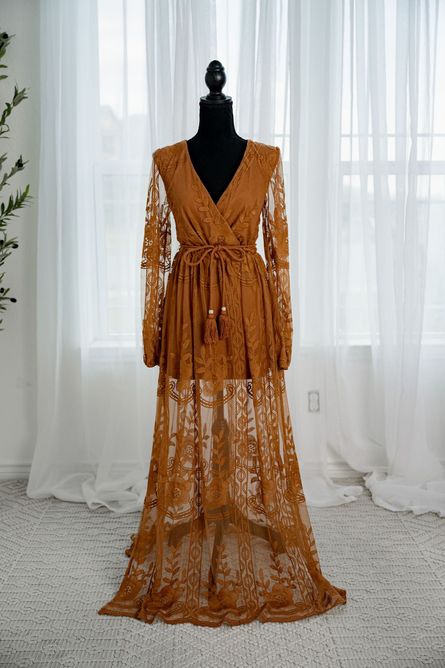 Caramel brown lace wrap maxi dress with long sleeves and tassel tie on a black mannequin.