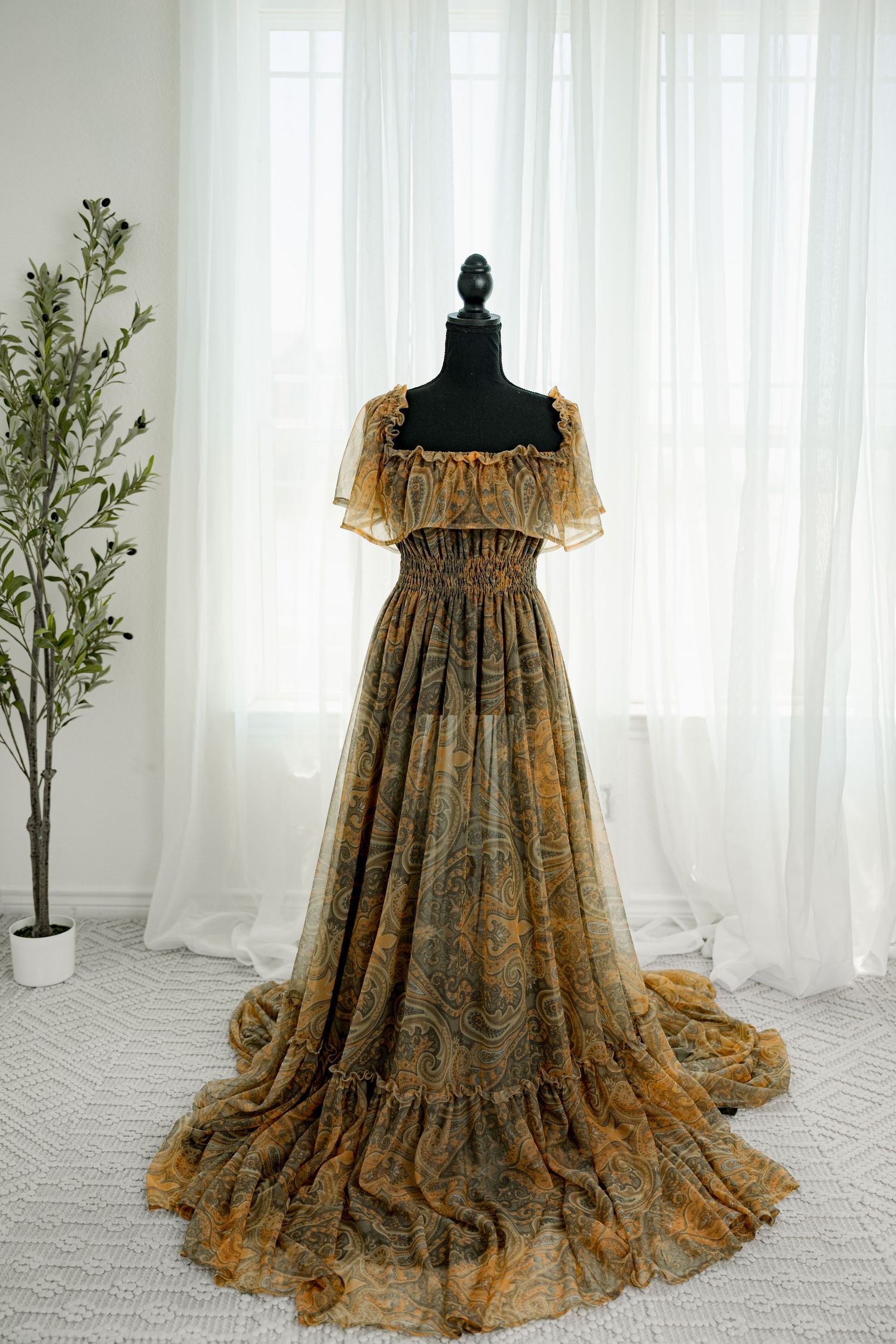 Gold paisley print off-shoulder tiered chiffon gown on mannequin.