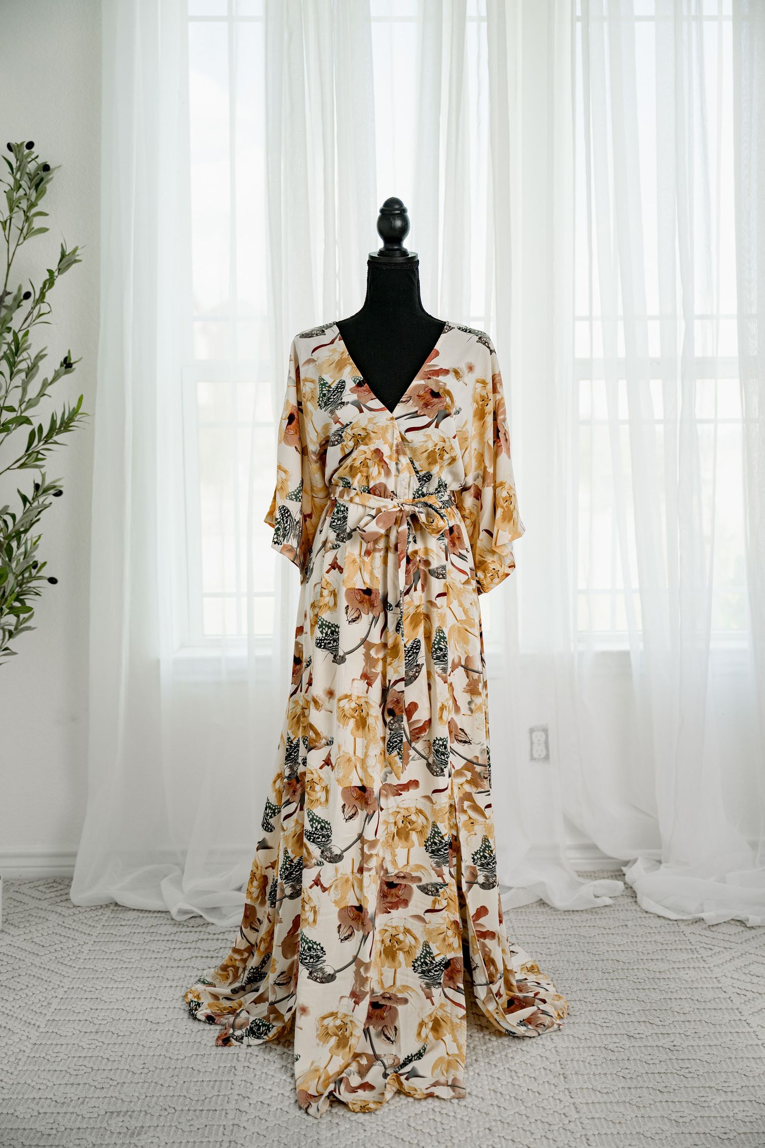 Cream floral print wrap maxi dress with flutter sleeves and tie waist on a mannequin.