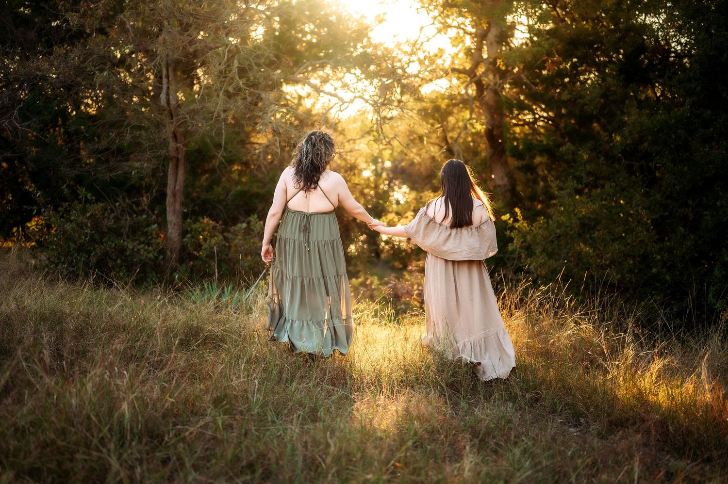Two people walking through a field at golden hour.