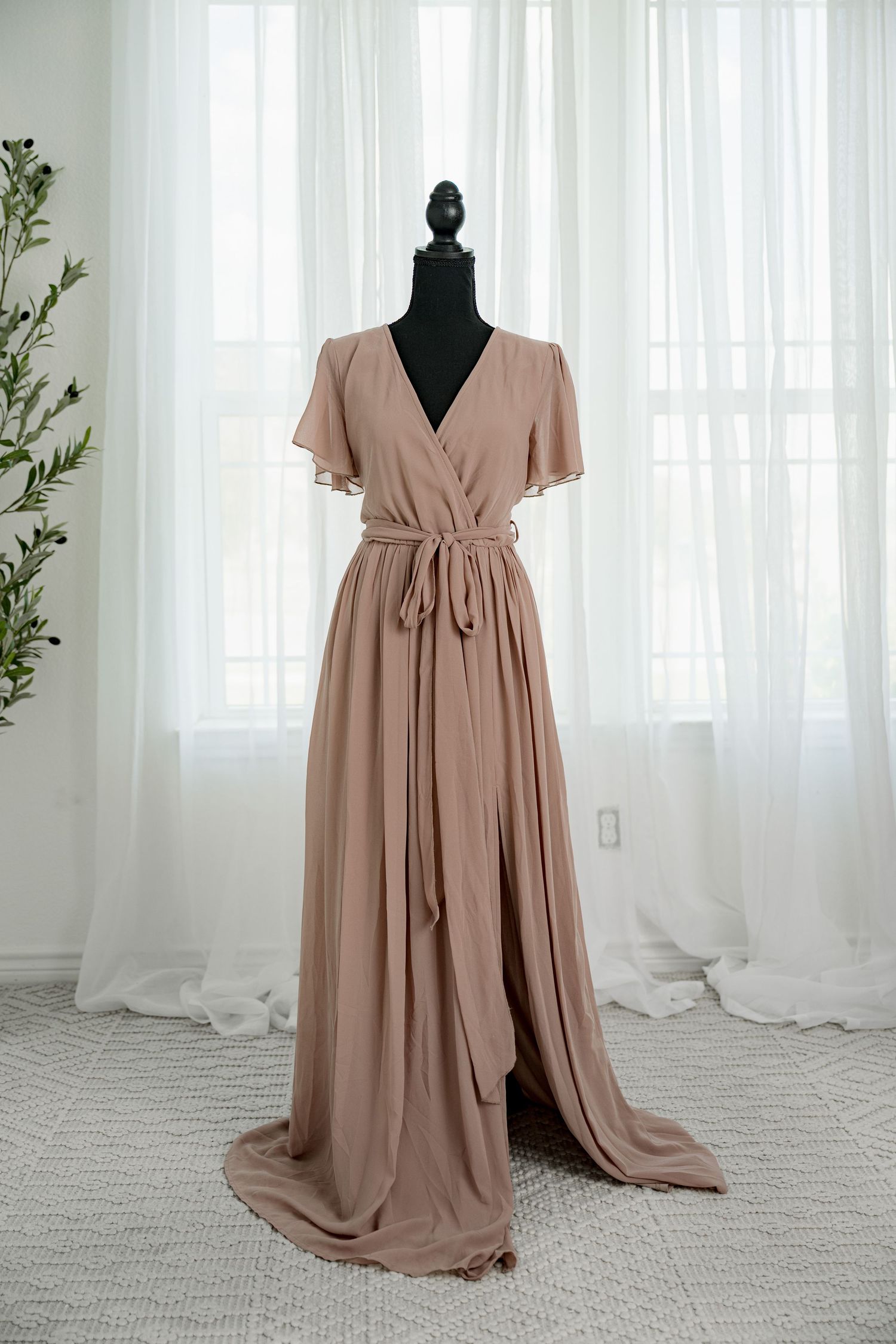 Elegant taupe chiffon wrap maxi dress with flutter sleeves and tie waist on a black mannequin.