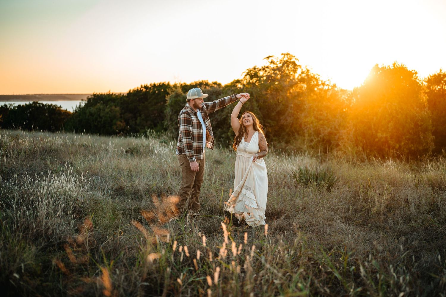 Couple dancing together in a golden field during a stunning sunset with warm glowing light.