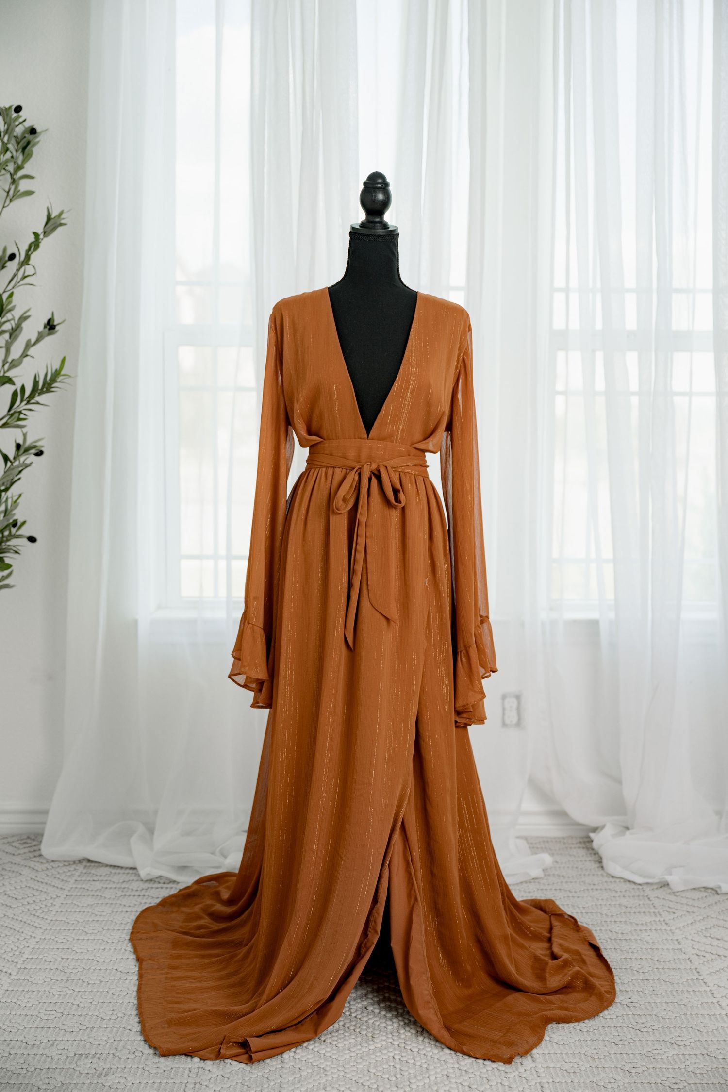 Burnt orange deep V-neck long sleeve wrap maxi dress with train on a black mannequin.