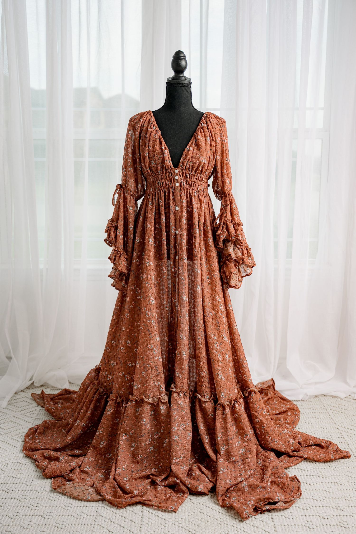 Burnt orange floral chiffon maxi dress with long ruffle sleeves on black mannequin.