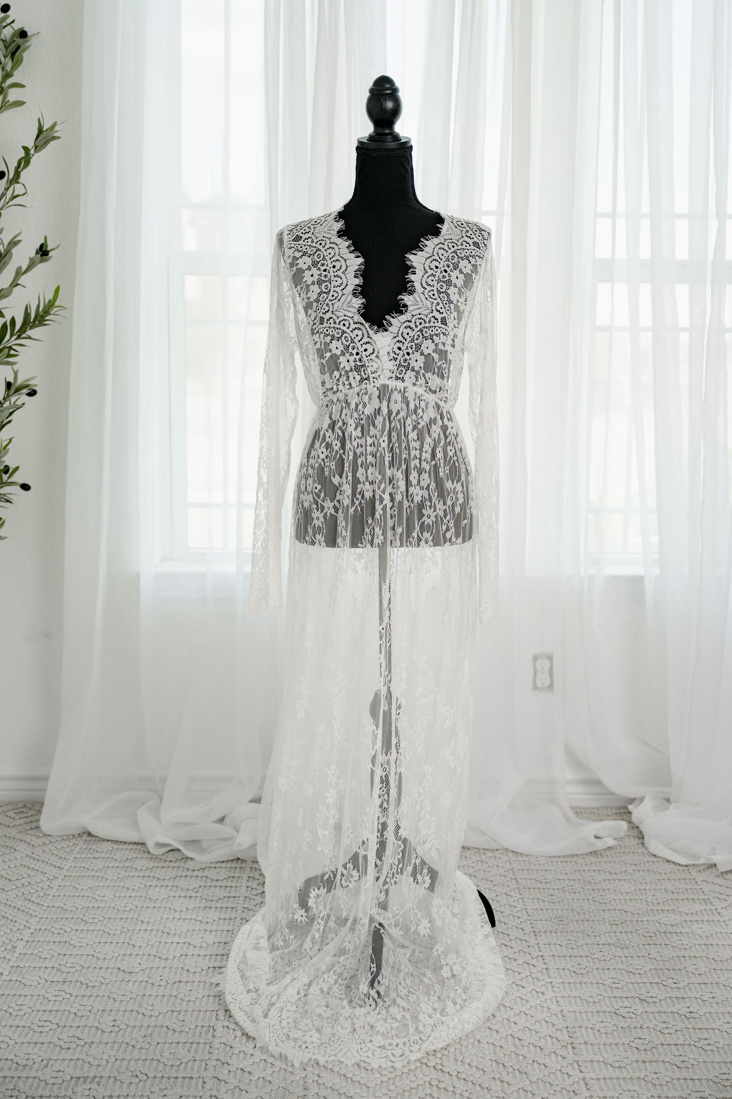 Sheer white lace cape sleeve maxi dress with floral embroidery on a black mannequin.