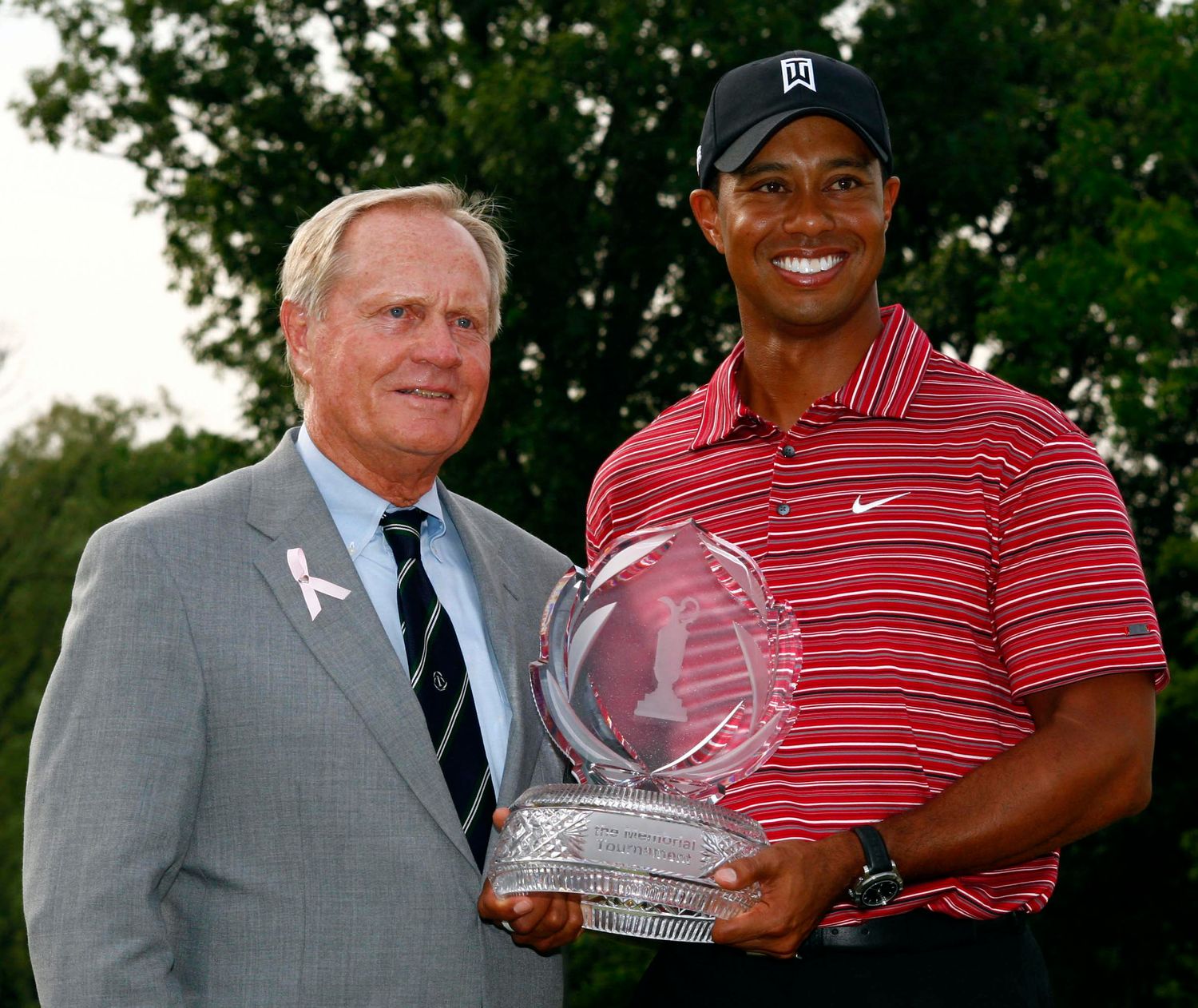 Professional golfer displays trophy during award ceremony on golf course.