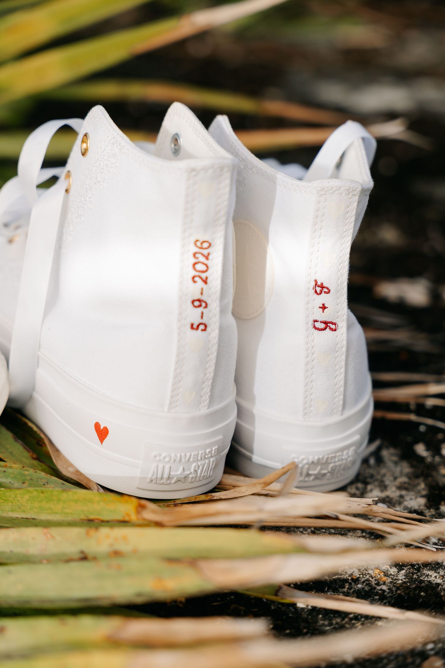 Custom white Converse high-tops with wedding date 5-9-2026 and red heart embroidery on palm leaves.