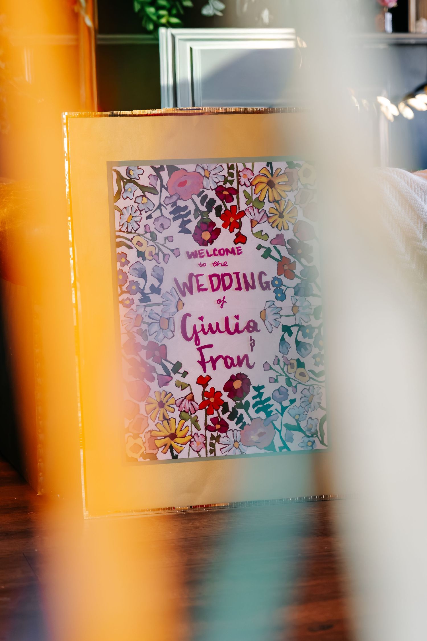 Floral wedding welcome sign reading Welcome to the Wedding of Giulia and Fran displayed on an easel.