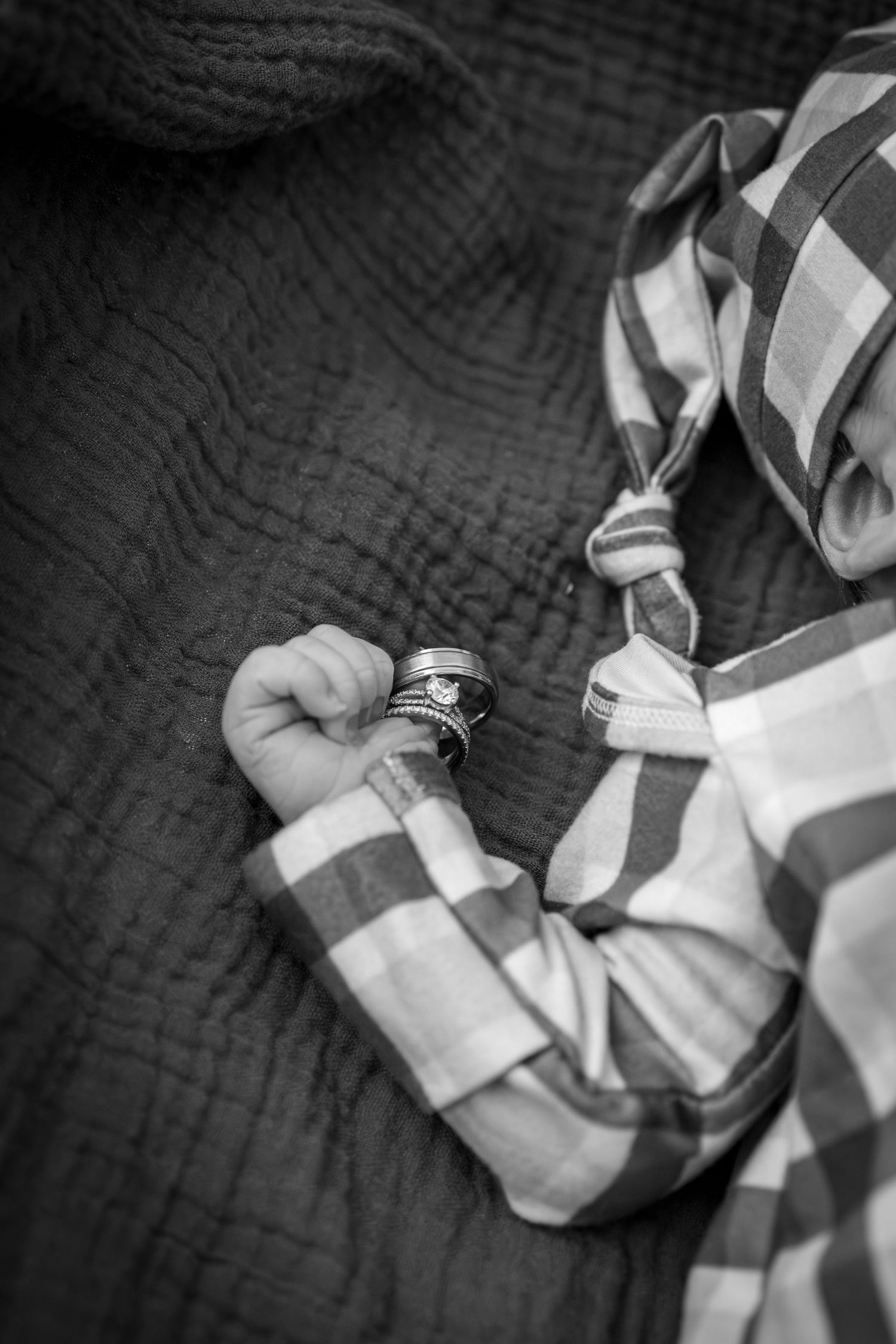 Newborn holding on to parents wedding rings with tiny fingers