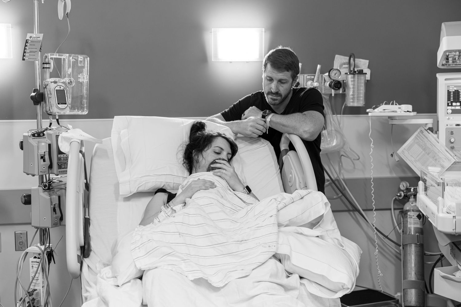 Mother holding her newborn moments after birth with emotional family-centered birth photography.