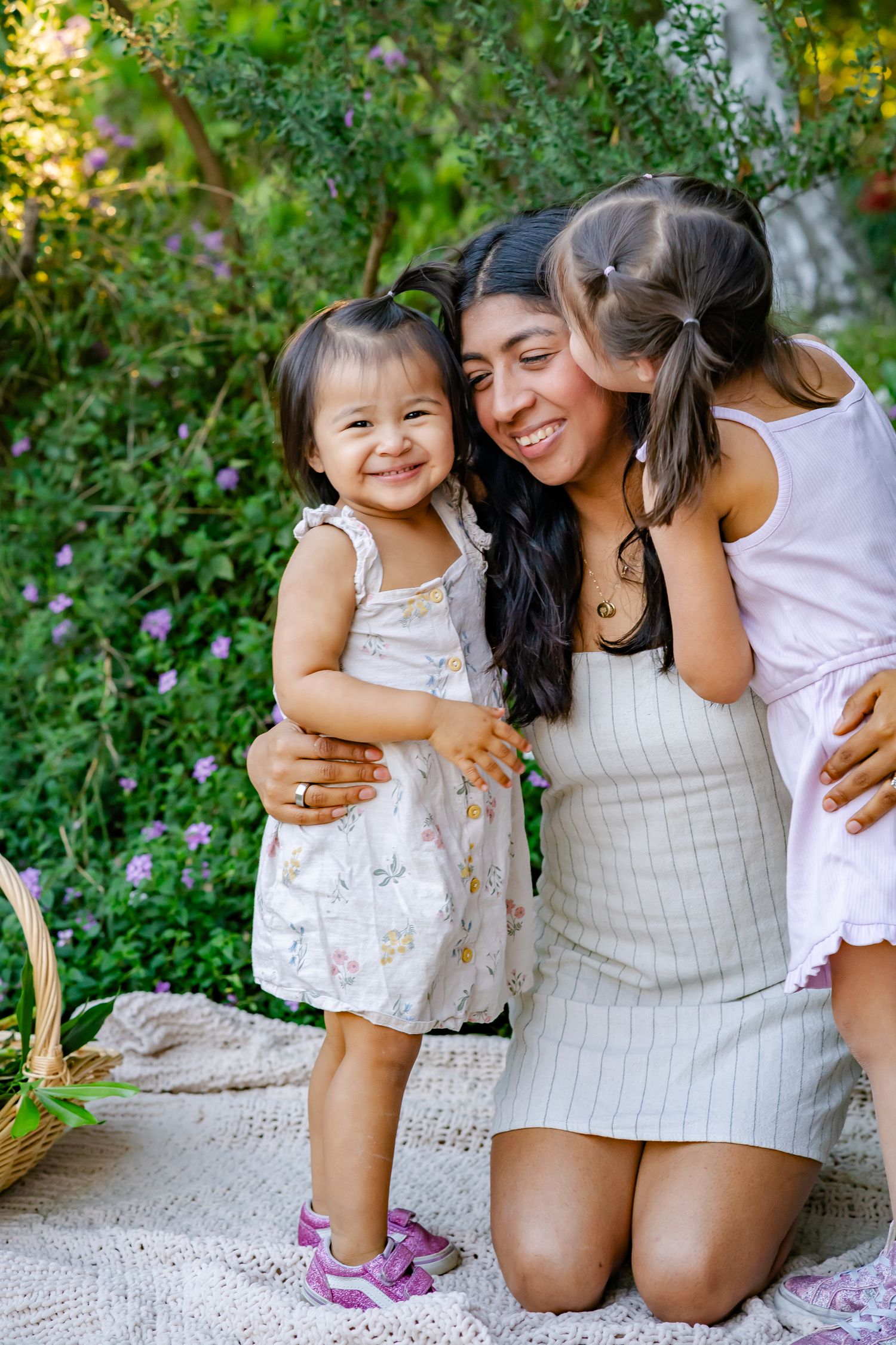 mom and daughters embrace and giggle on a warm, spring evening