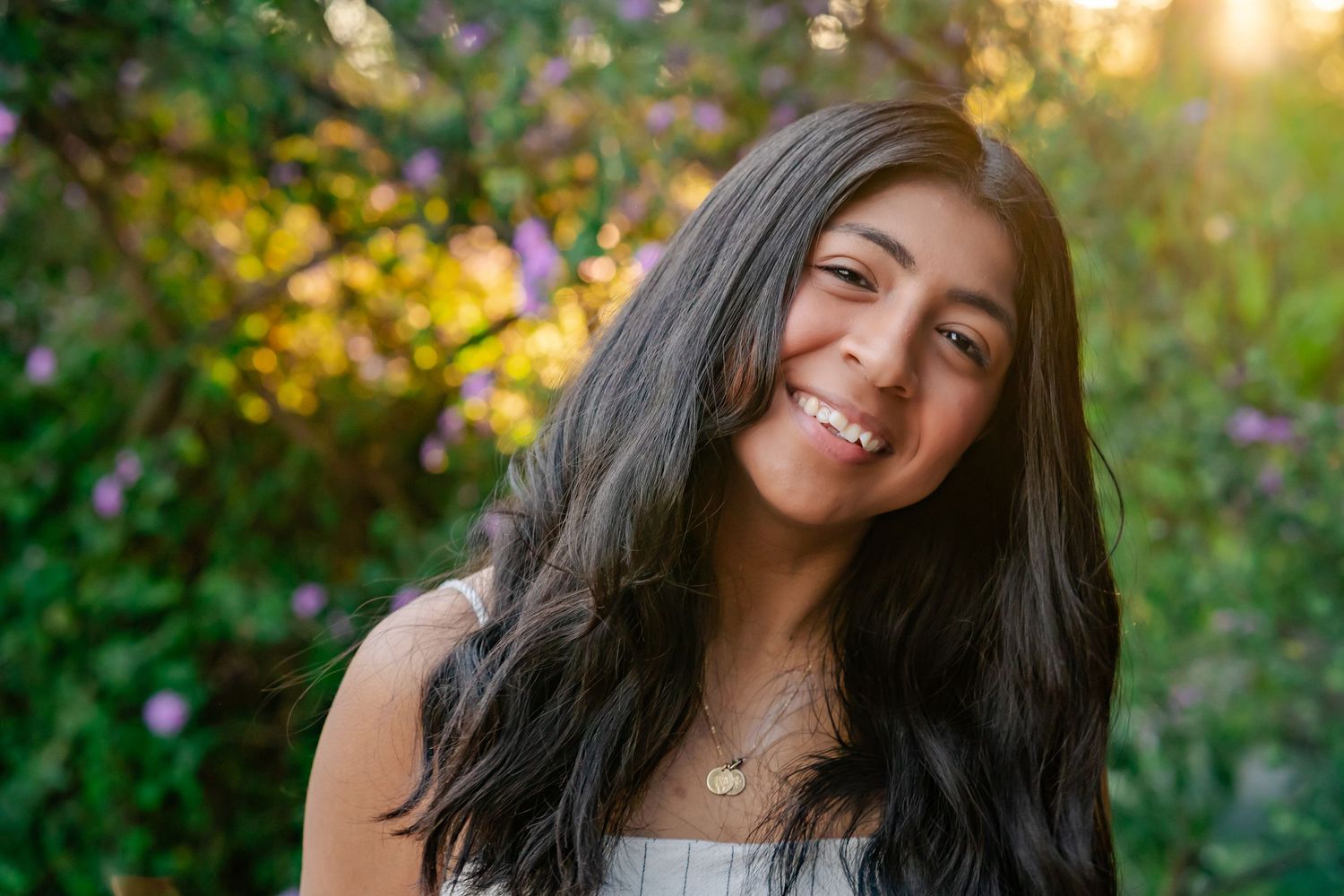 headshot of mom influencer with golden sun glow behind her and vibrant greenery in the background