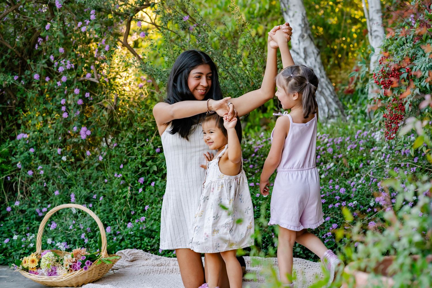 mom and daughters dance outside in the flowers