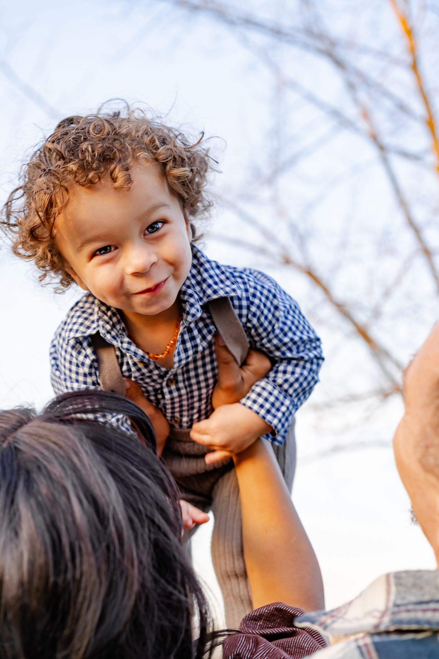 mom holds baby boy in the air and soft sunset lighting lights up his face