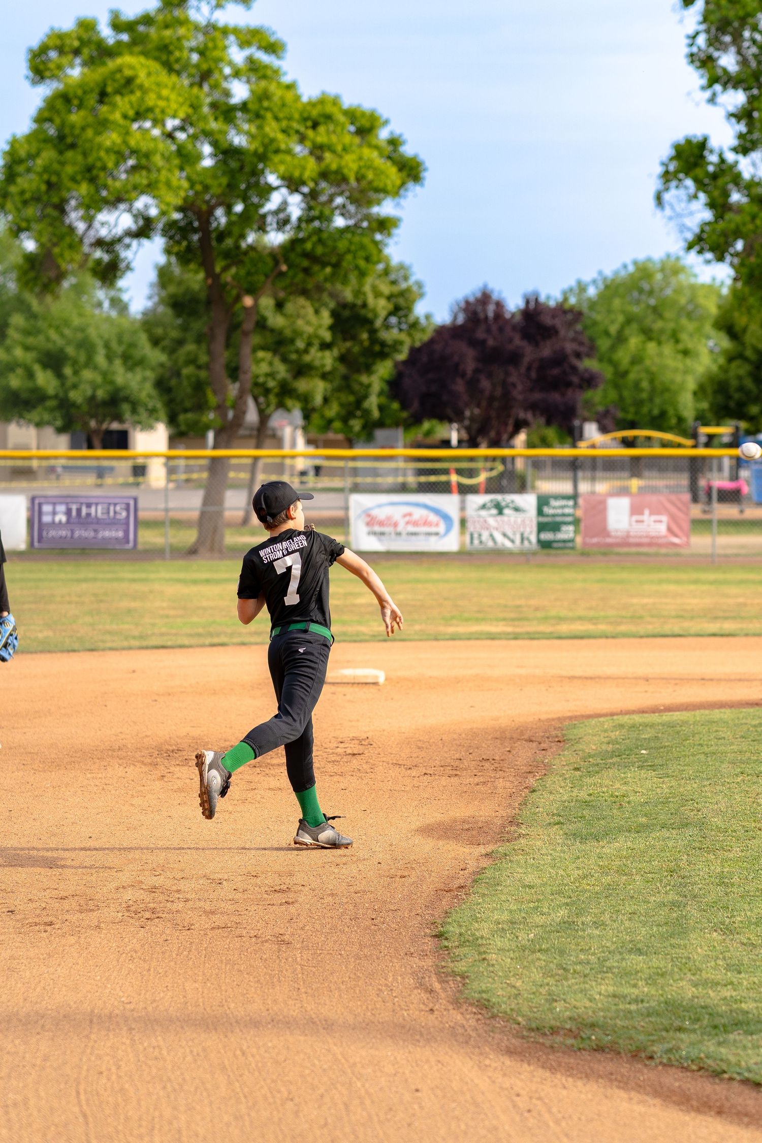 Young softball pitcher delivering a pitch during league play in the Central Valley.