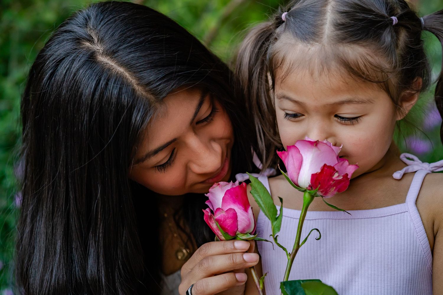 mom and daughter photo with roses that they are smelling together