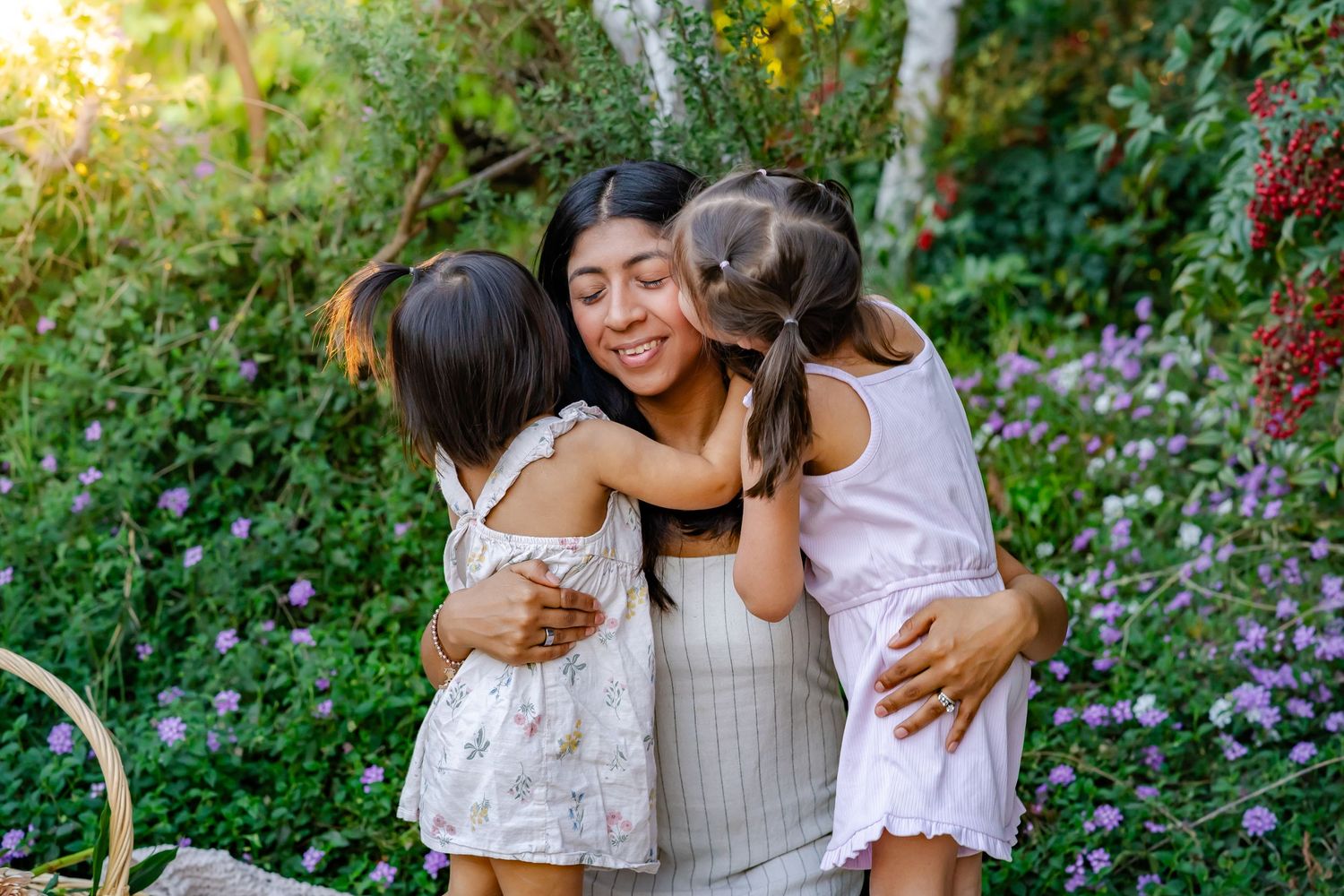 girls kissing their mom on both sides of her face during golden hour in Turlock