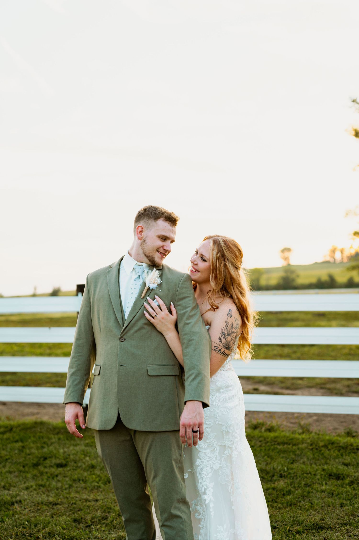 Romantic sunset portrait session on grassy field near water with soft golden hour lighting.