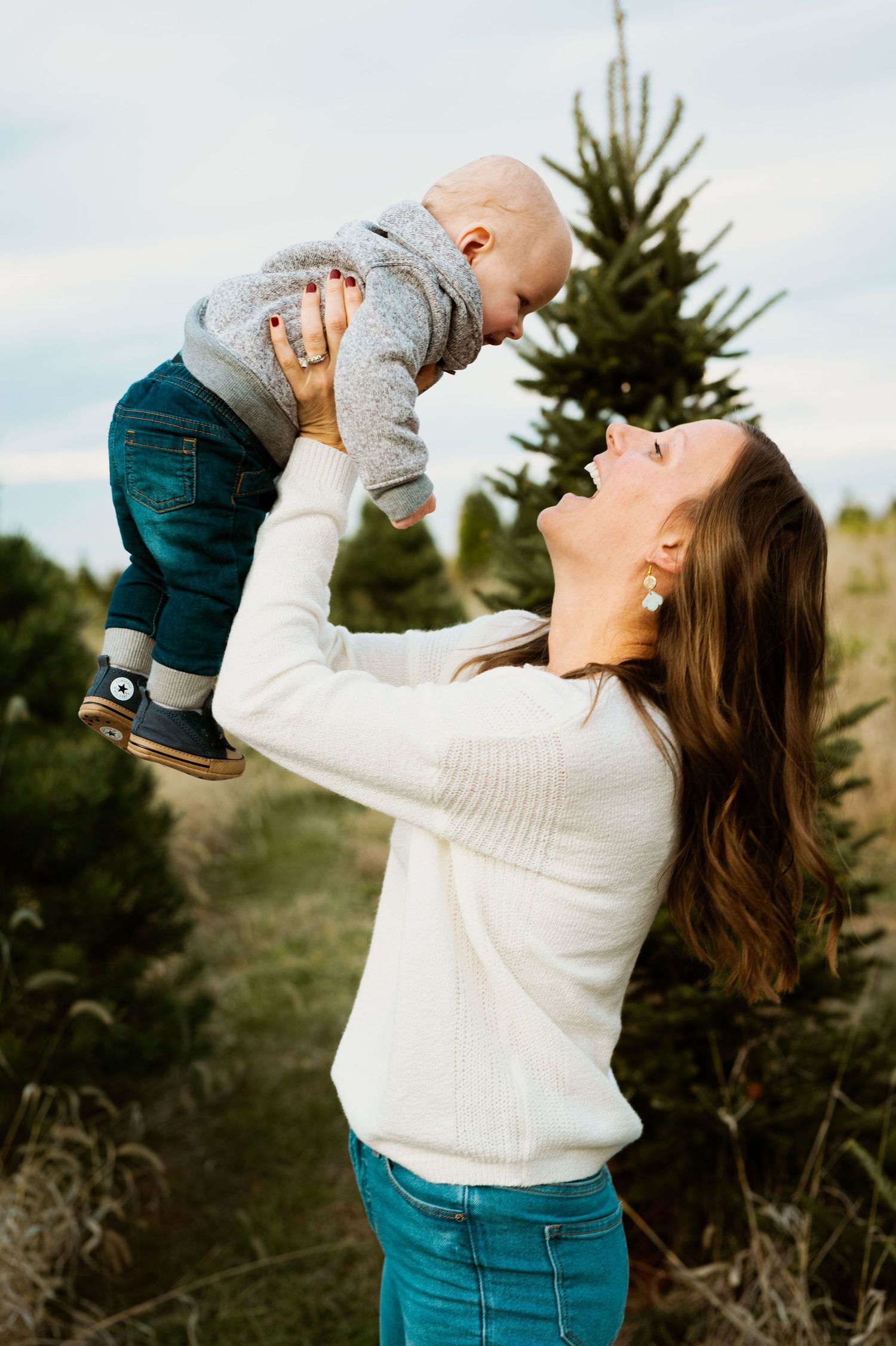 Joyful moments captured as a parent lifts and plays with a small child against an outdoor backdrop.