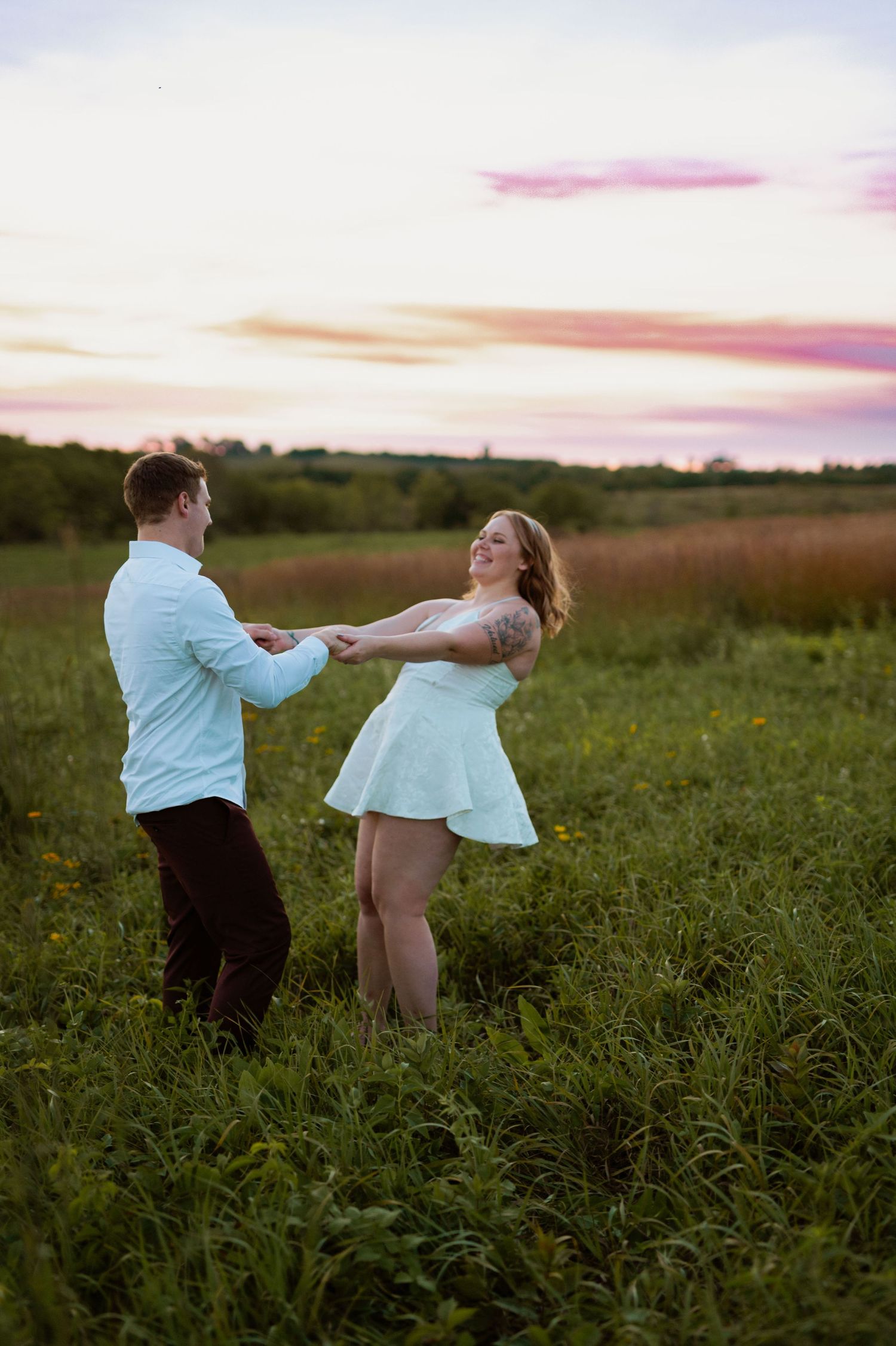 A couple dances together in a field during a sunset photo session.