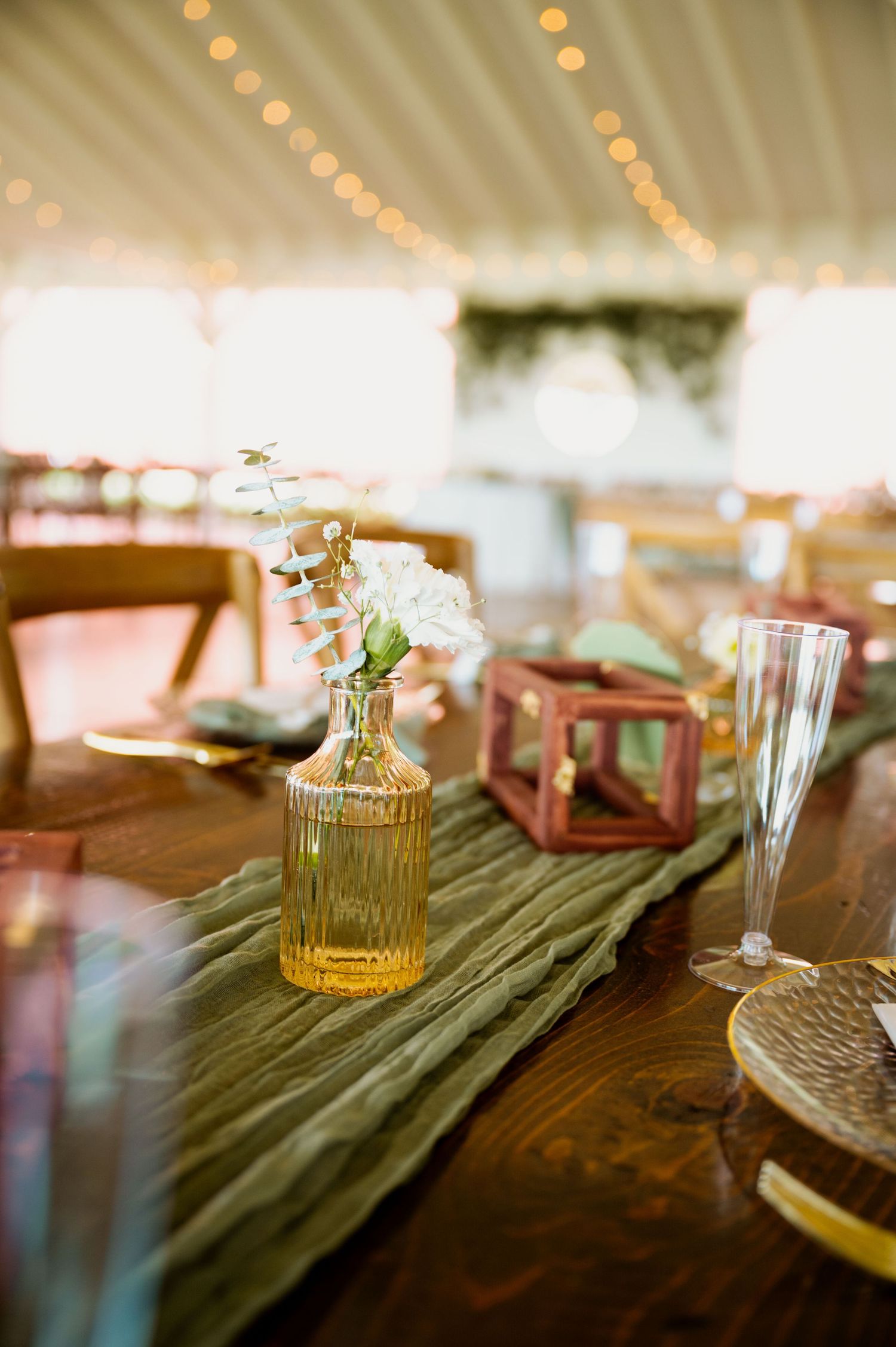 Wedding table settings with vintage glass bottles and teal runners on wooden tables.