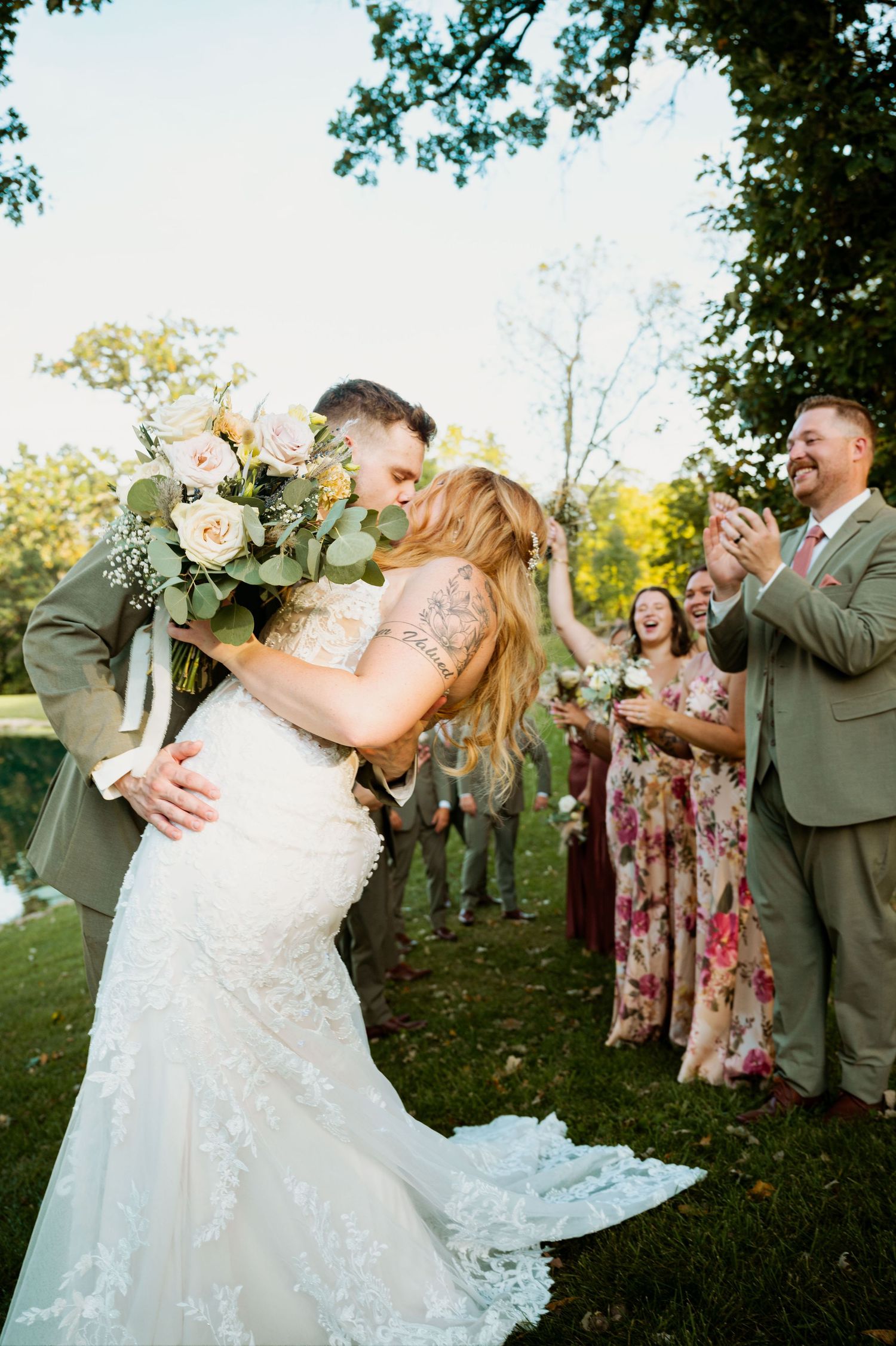 Celebratory wedding moment with couple dancing outdoors surrounded by guests in floral dresses.