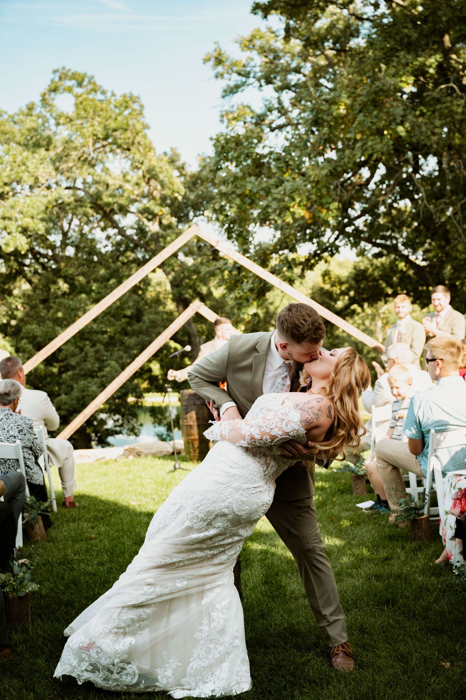 Wedding couple performs a dramatic dip kiss while guests hold sparklers creating a magical outdoor moment.