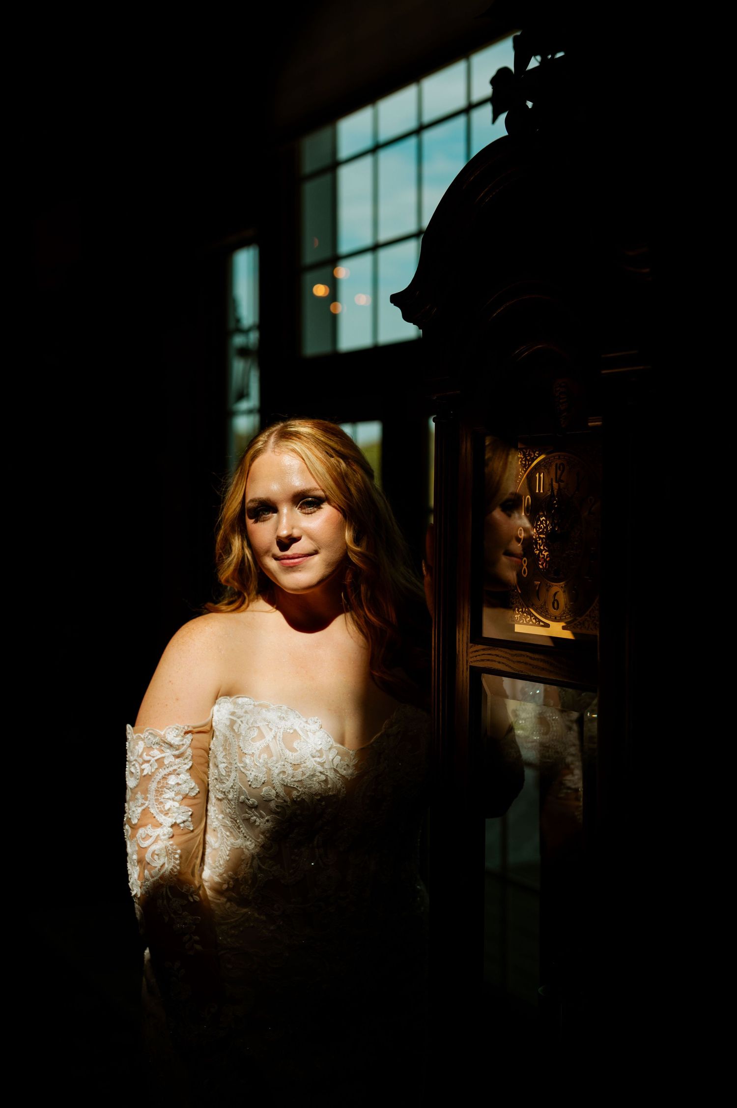 A dramatic bridal portrait in moody lighting with a window casting shadows and reflections.