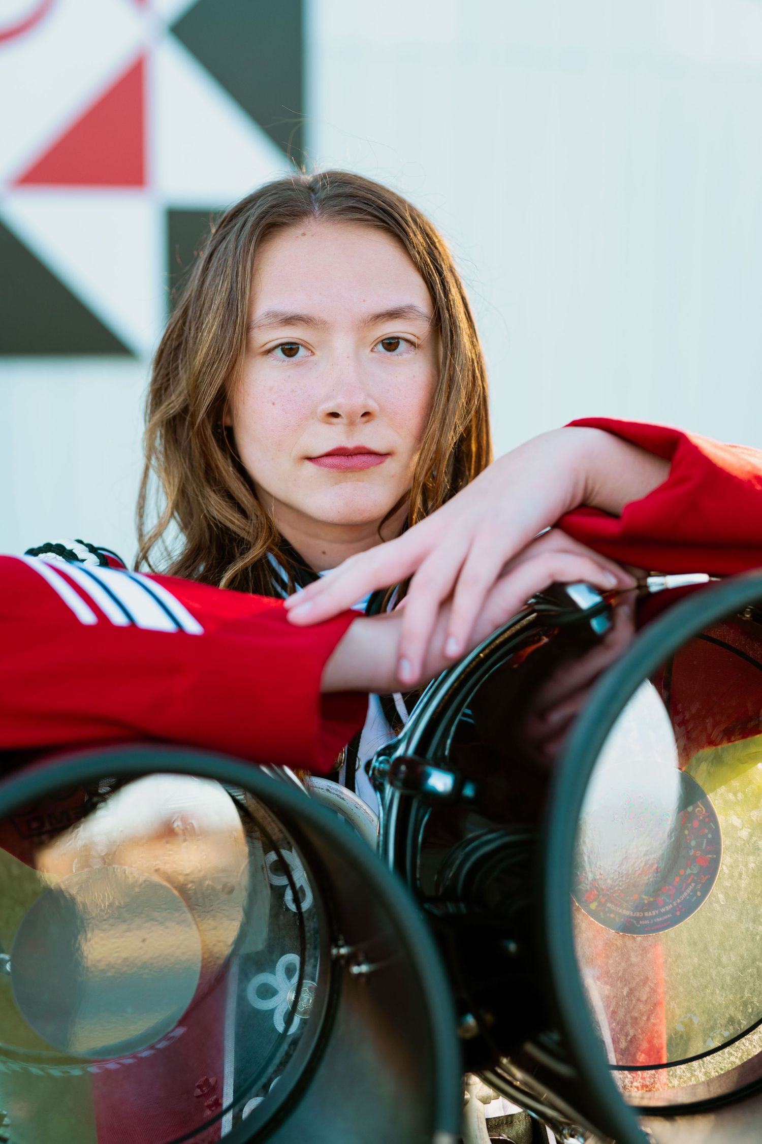 Close-up portrait with colorful stage lights and geometric background pattern.