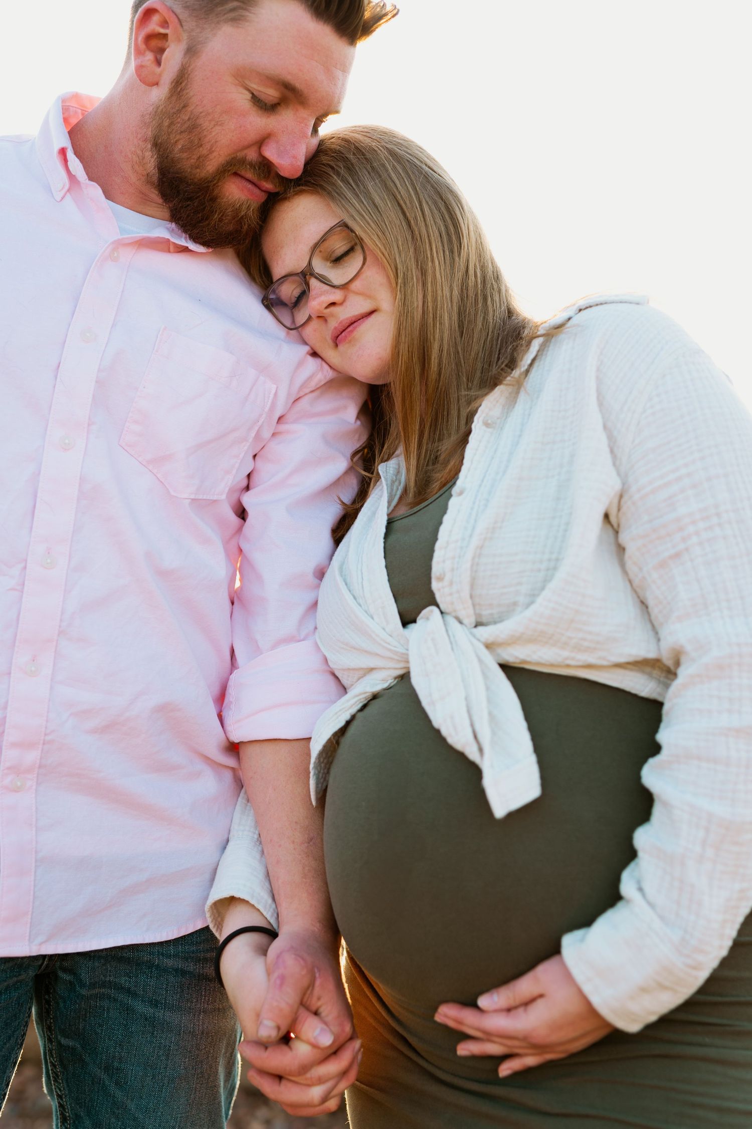 A couple shares an intimate moment touching a pregnant belly in a series of tender maternity photos.