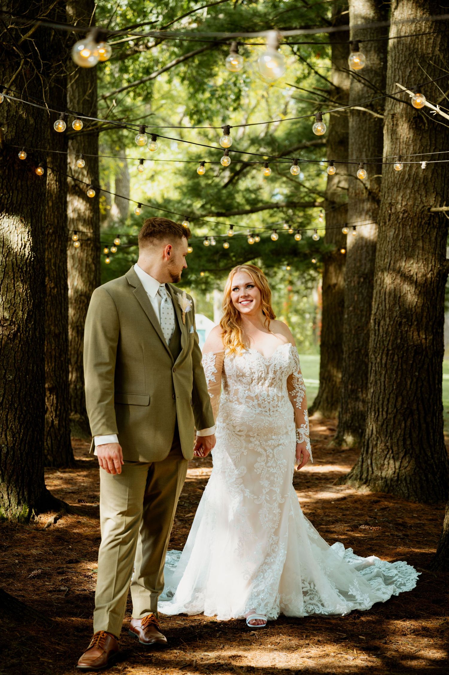 A romantic woodland wedding scene with string lights and tall trees creating a natural ceremony backdrop.