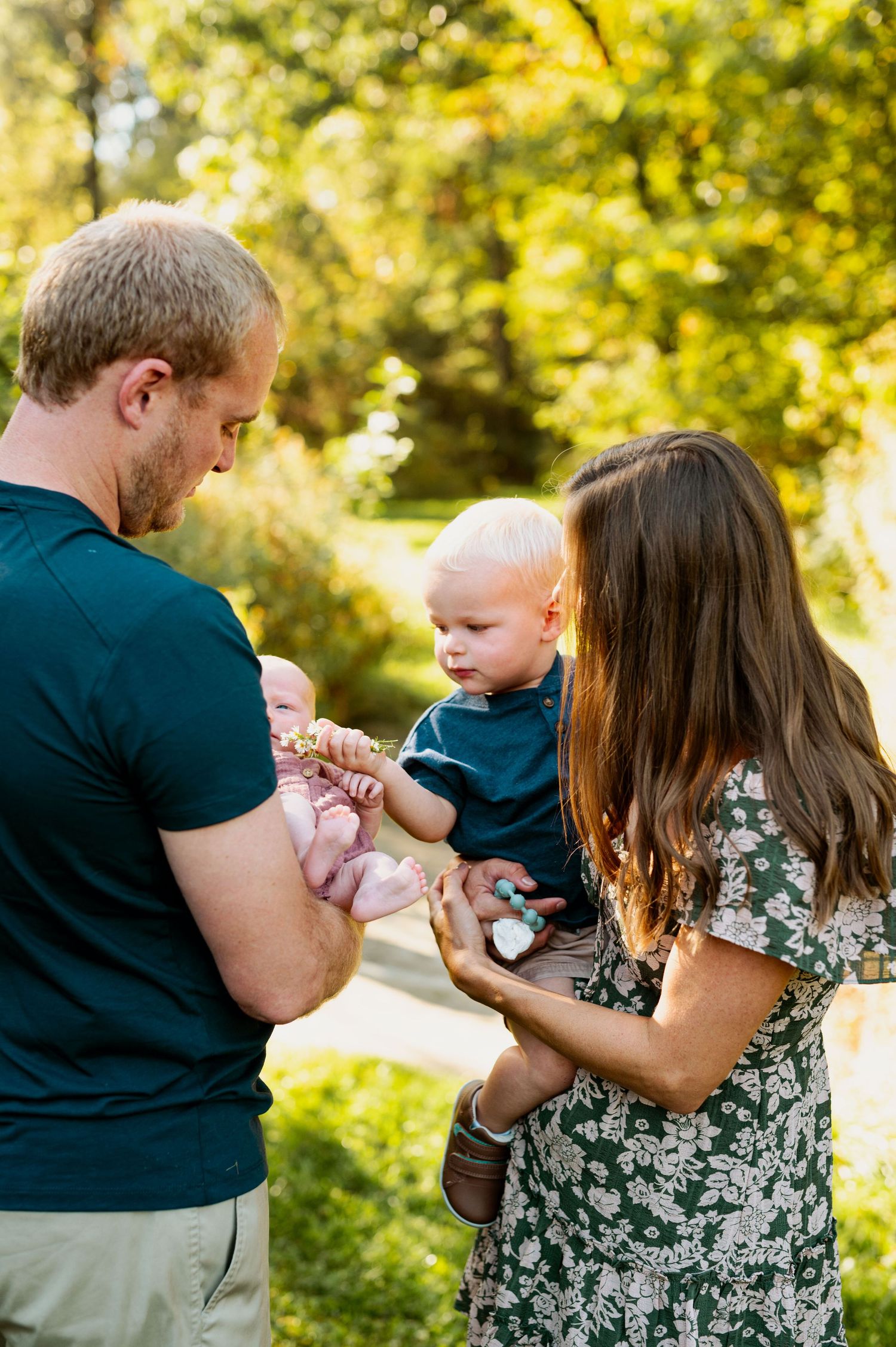 A family shares a tender moment together outdoors on a sunny day with golden bokeh lighting in the background.