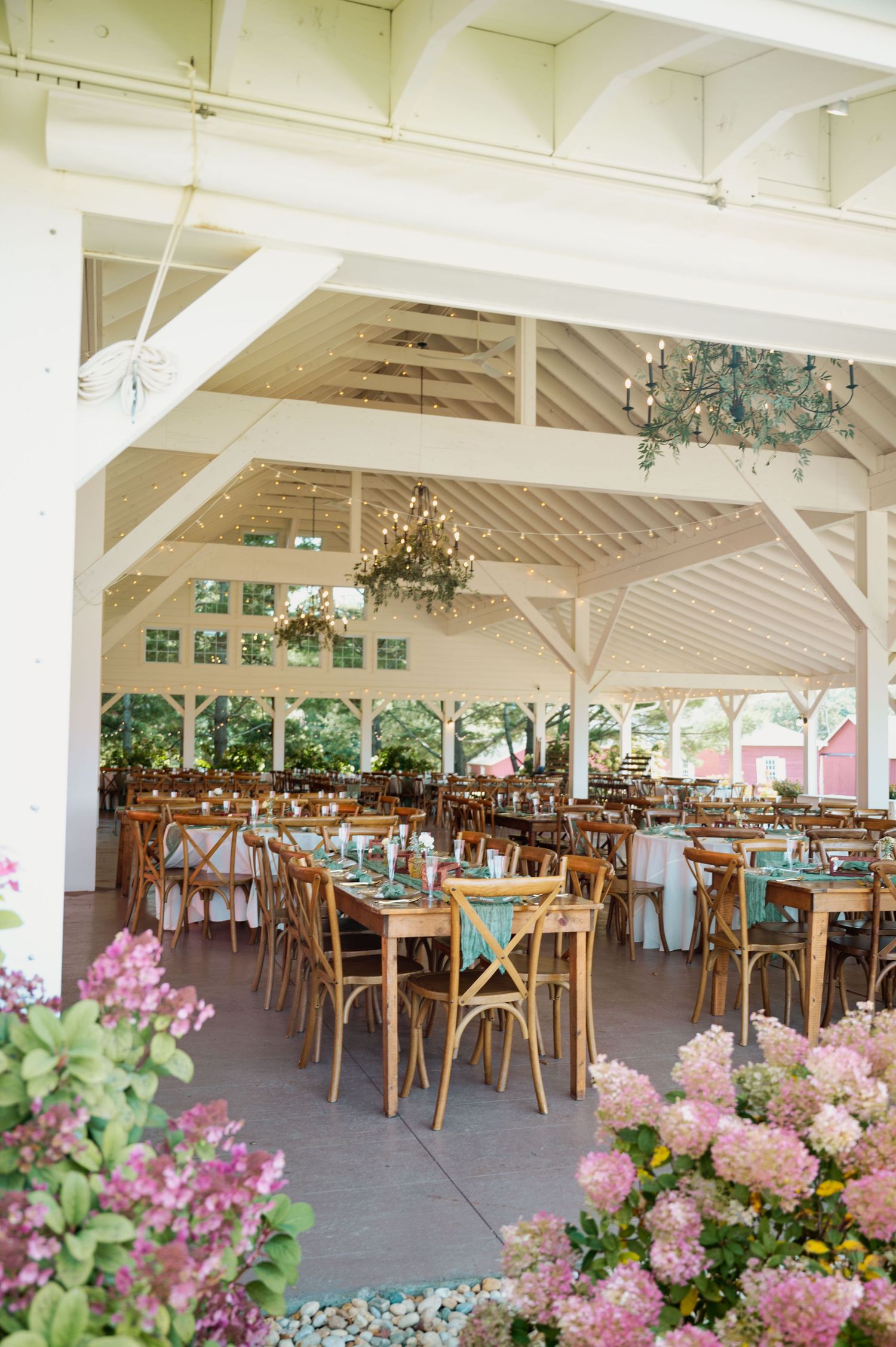 Elegant wedding reception venue with white beams and pink floral decorations.