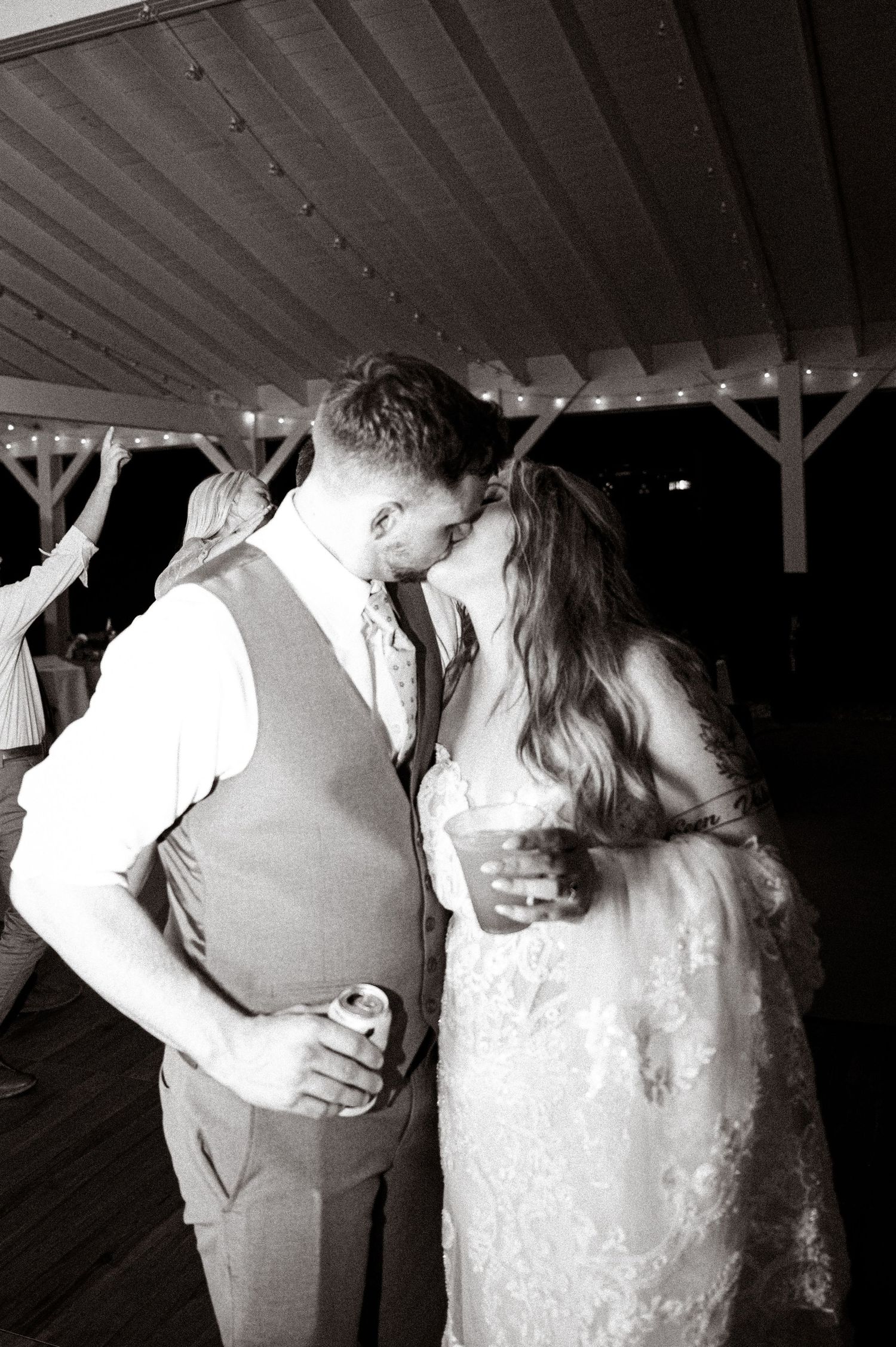 Black and white reception photo under string lights capturing an intimate dance moment.