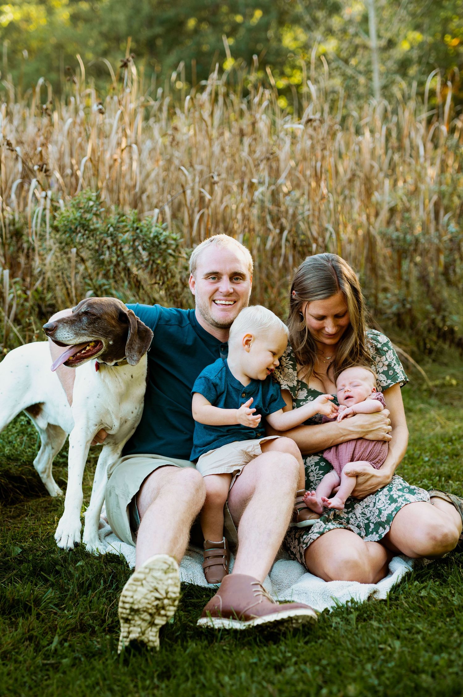 A family and their dog relax together on green grass during a warm summer afternoon.