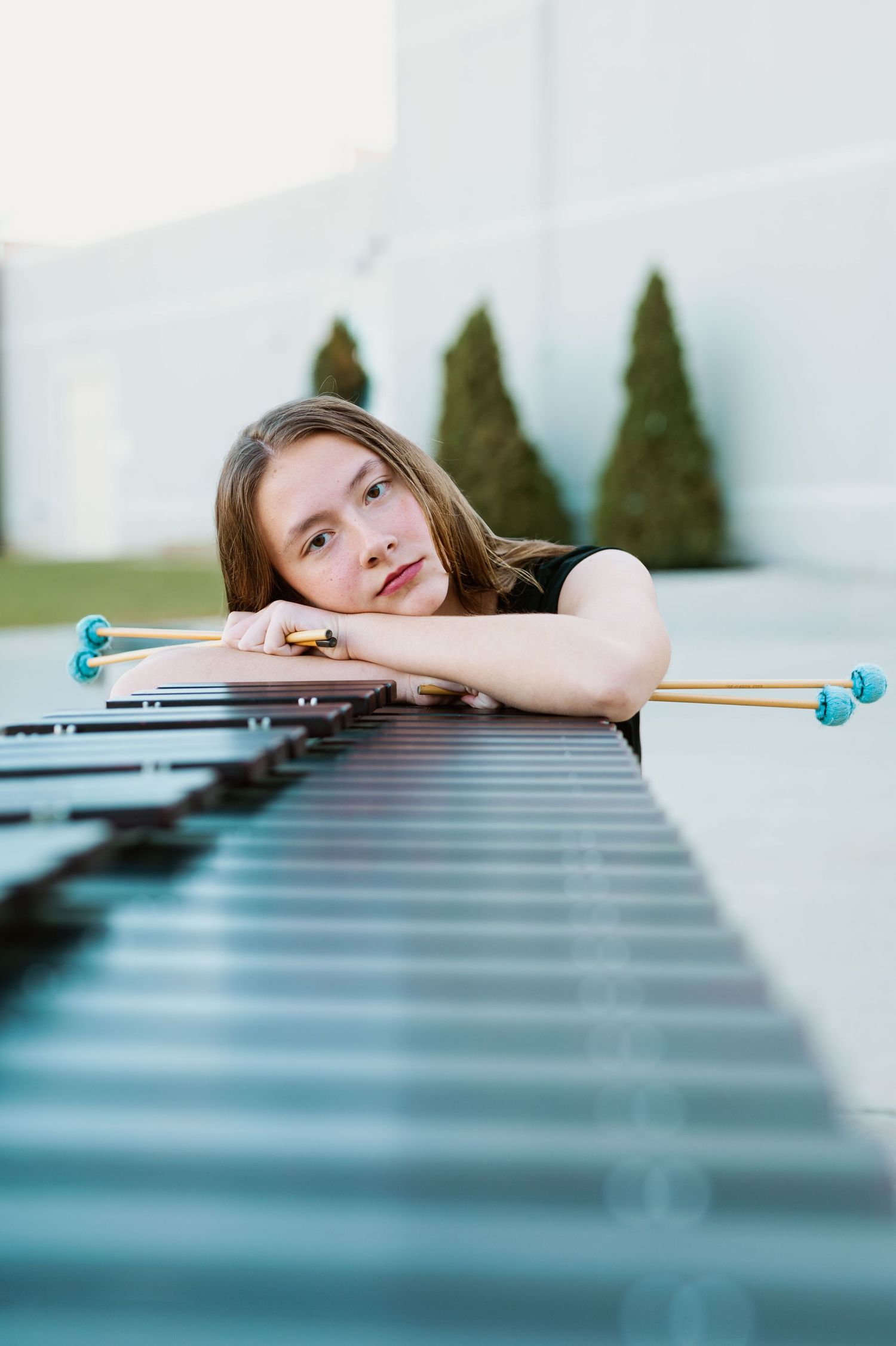 Creative portrait of girl resting her head on piano keys outdoors.