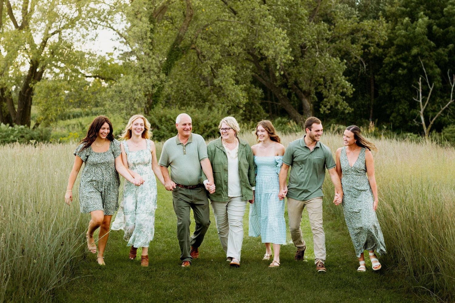A group of people in coordinating blue and white outfits running through a grassy field at sunset.