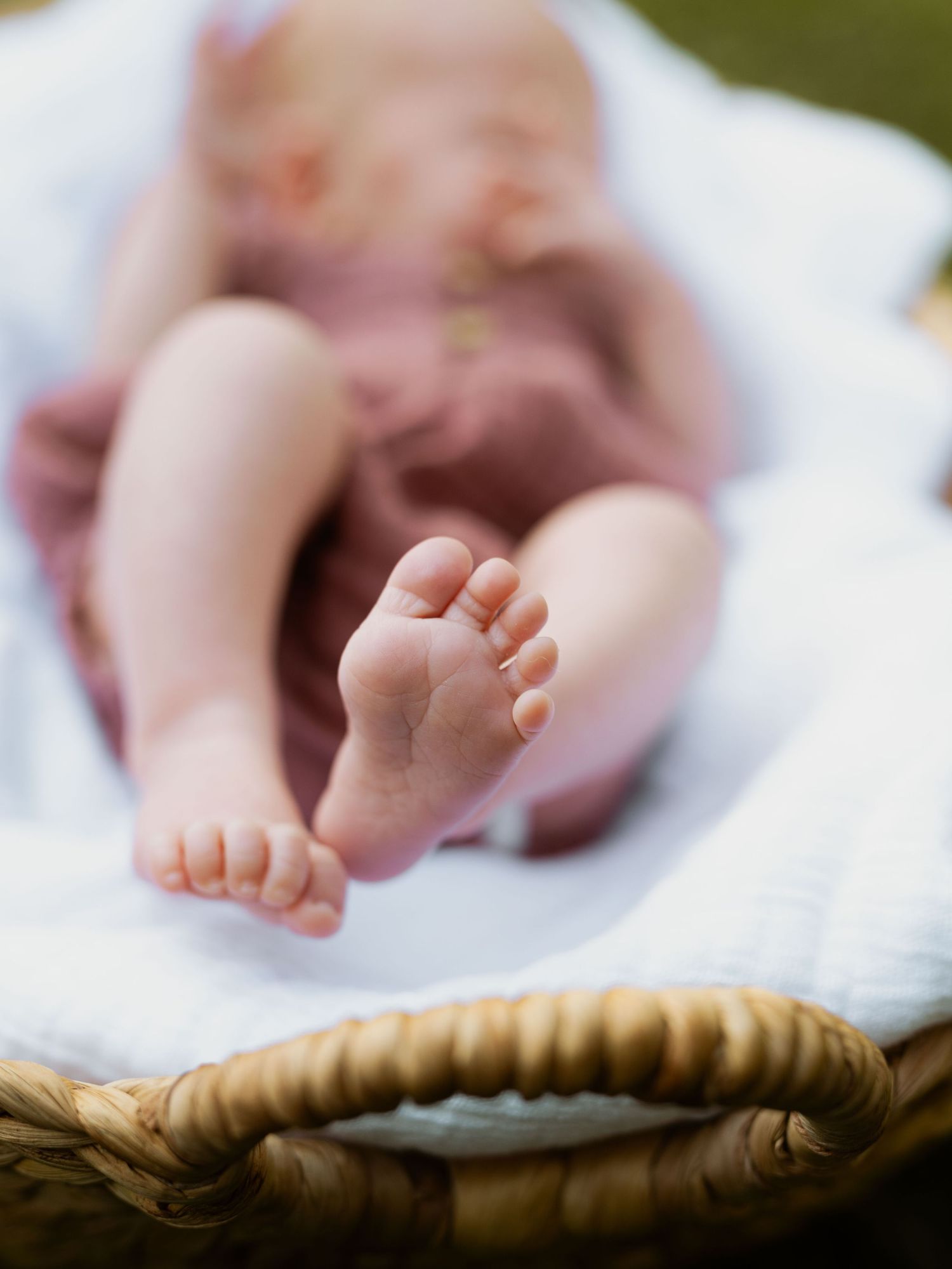 Close up of tiny baby feet against white blanket and natural backdrop.