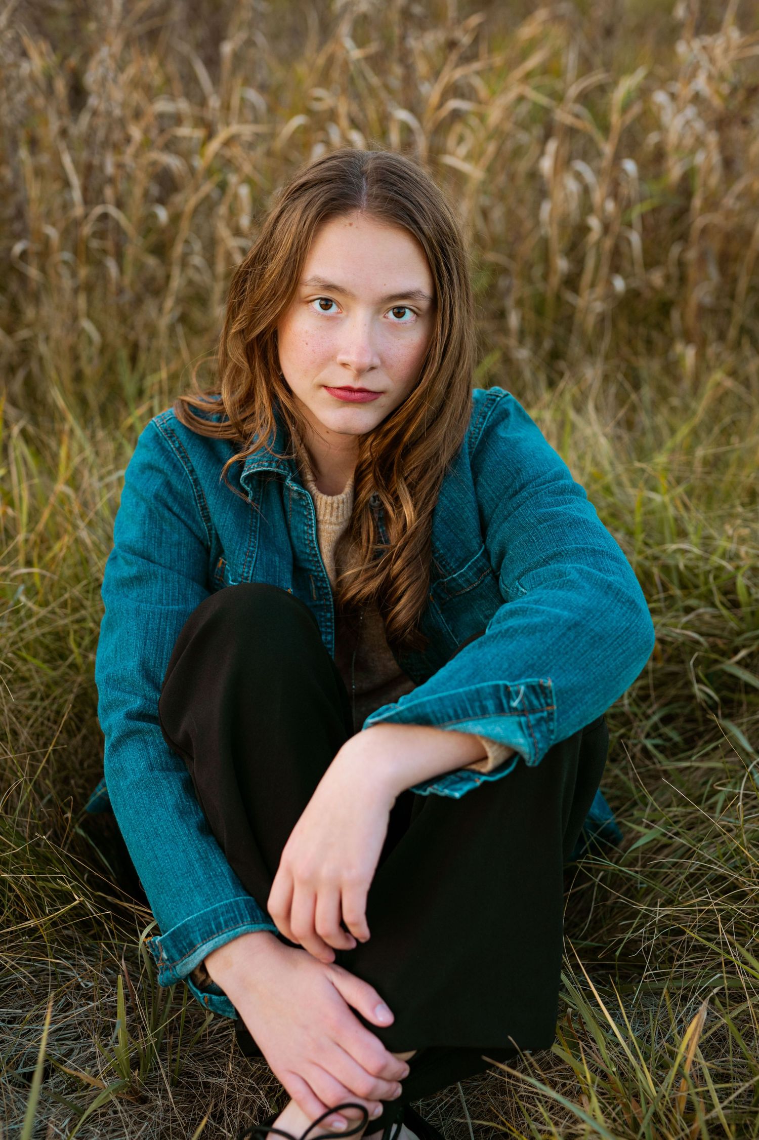 Portrait in teal jacket against autumn grass field background.
