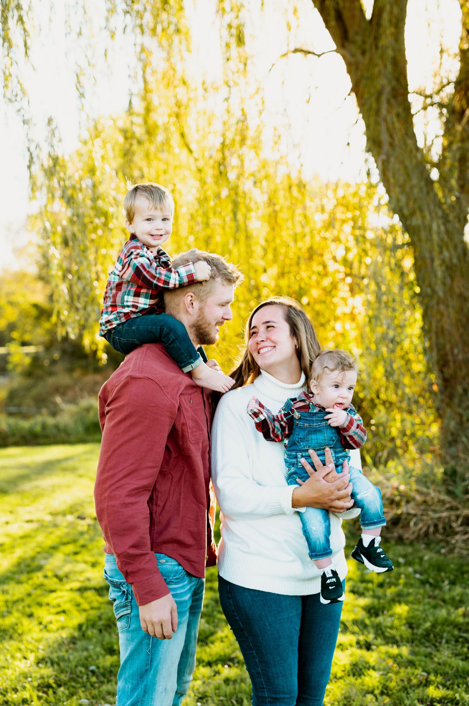 A family shares joyful moments together during an autumn photoshoot with golden trees in the background.