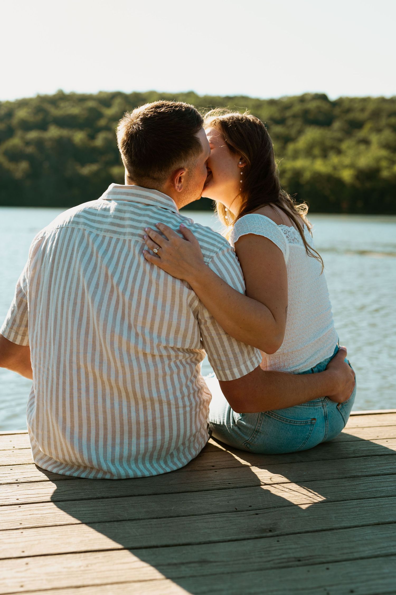 A couple sharing an intimate moment while sitting on a dock by the water.