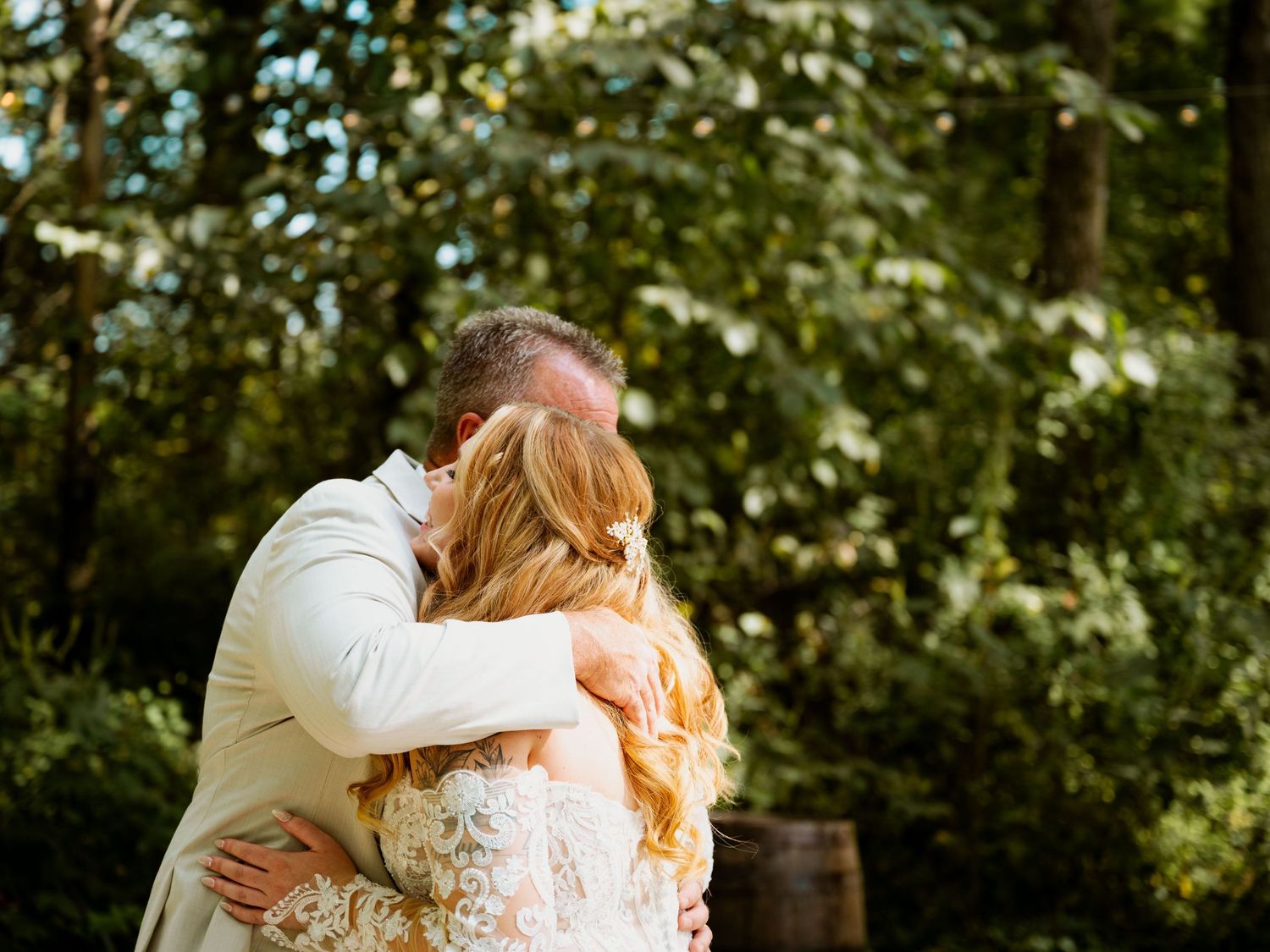 Romantic outdoor wedding moment captured in golden sunlight among trees.