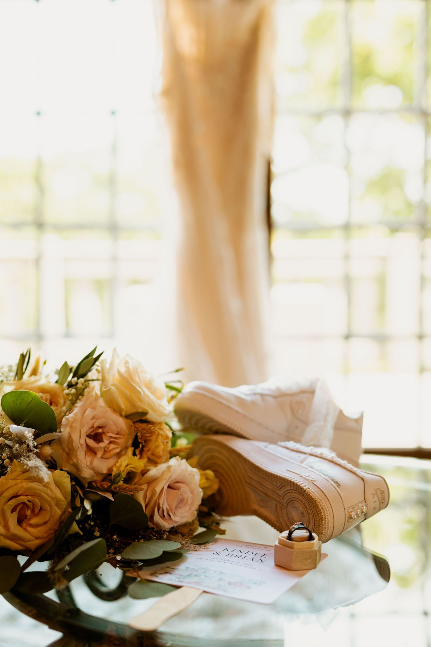 Delicate peach roses and wedding details arranged on a light surface with soft window lighting.