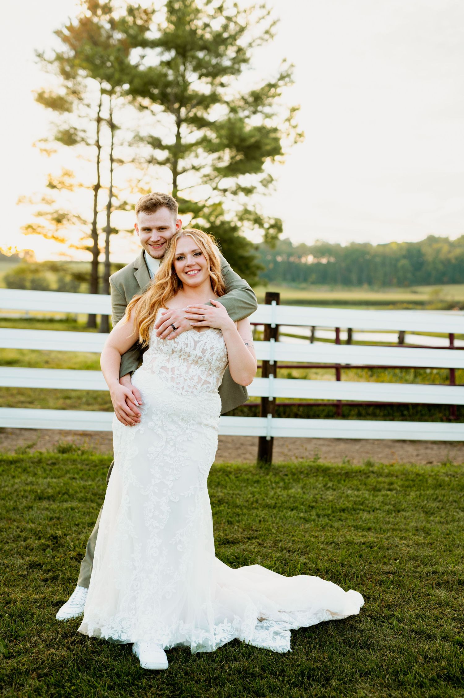 Intimate wedding portrait by a lakeside with golden hour lighting and pine trees in background.