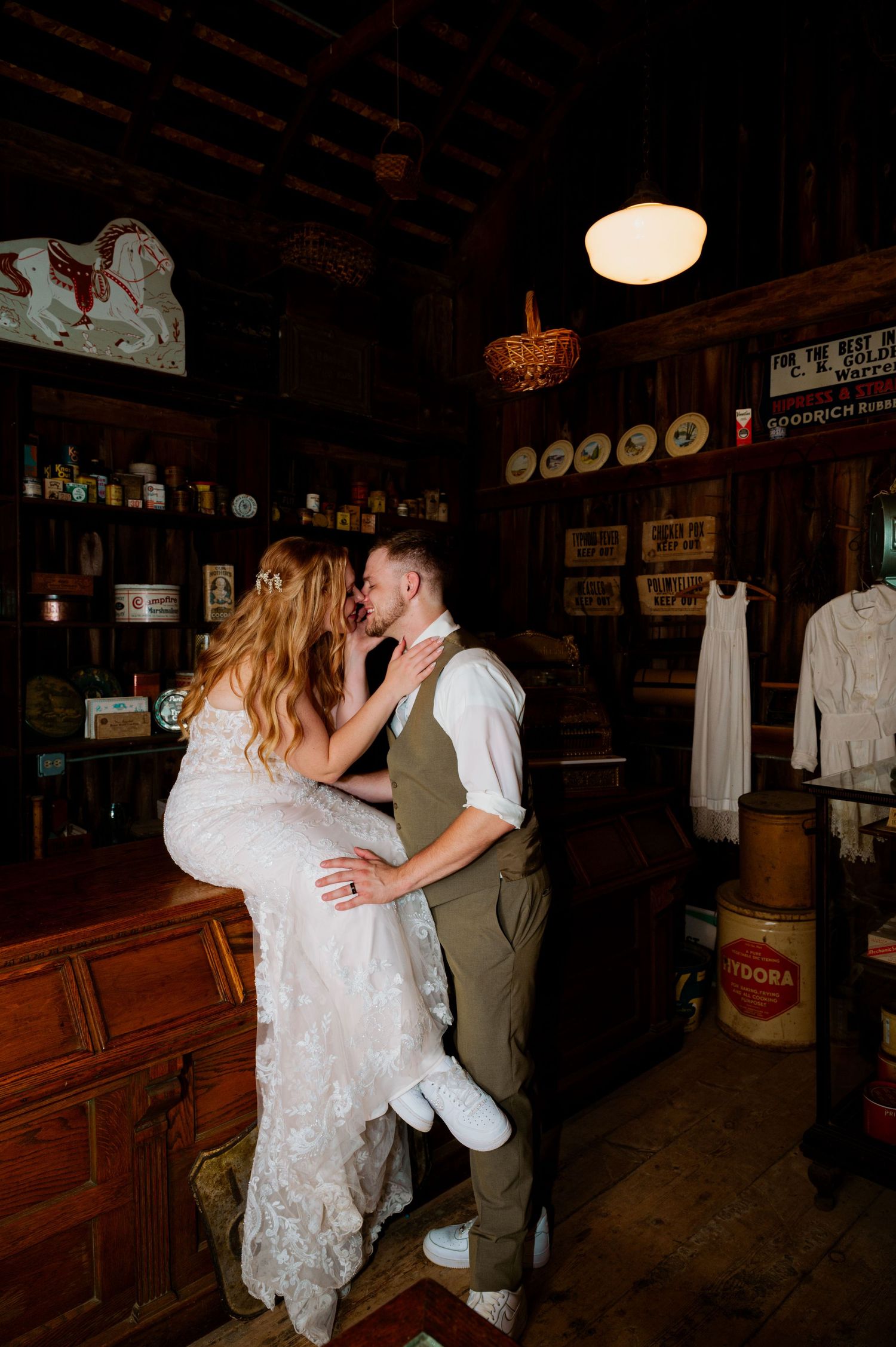 A romantic moment between newlyweds in a rustic barn setting with vintage decor and warm lighting.