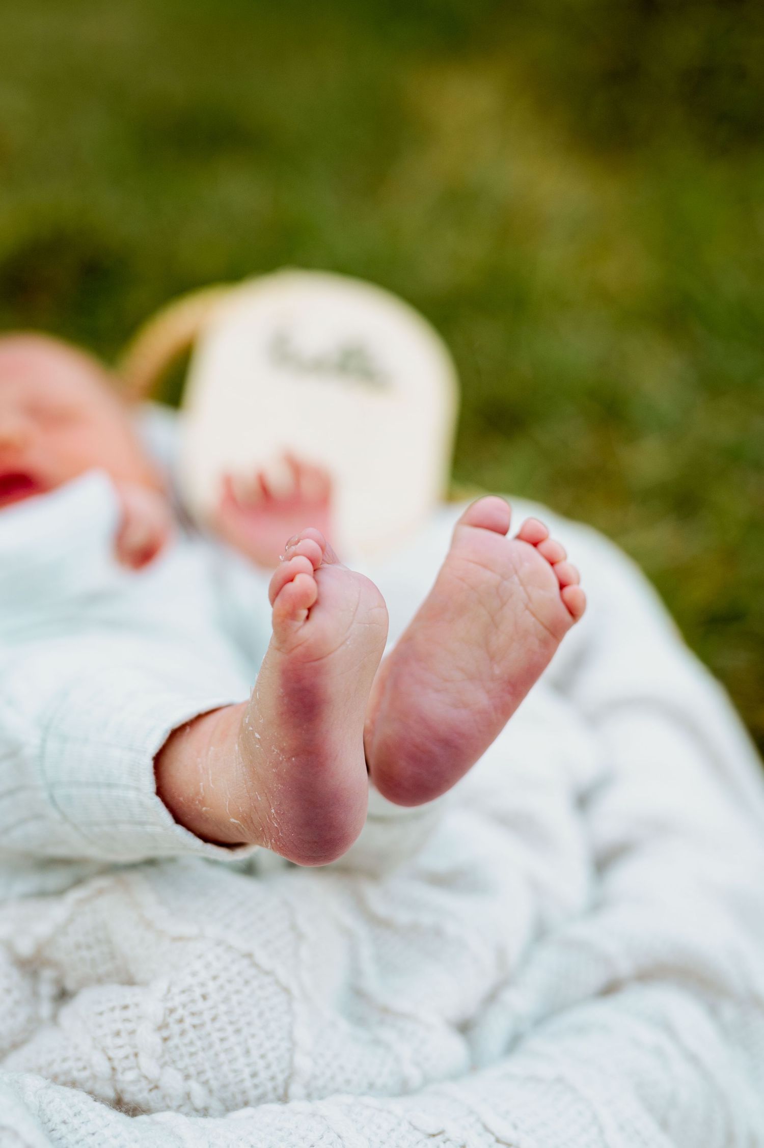 Tiny baby feet peeking out from a soft white blanket in a series of similar photos.